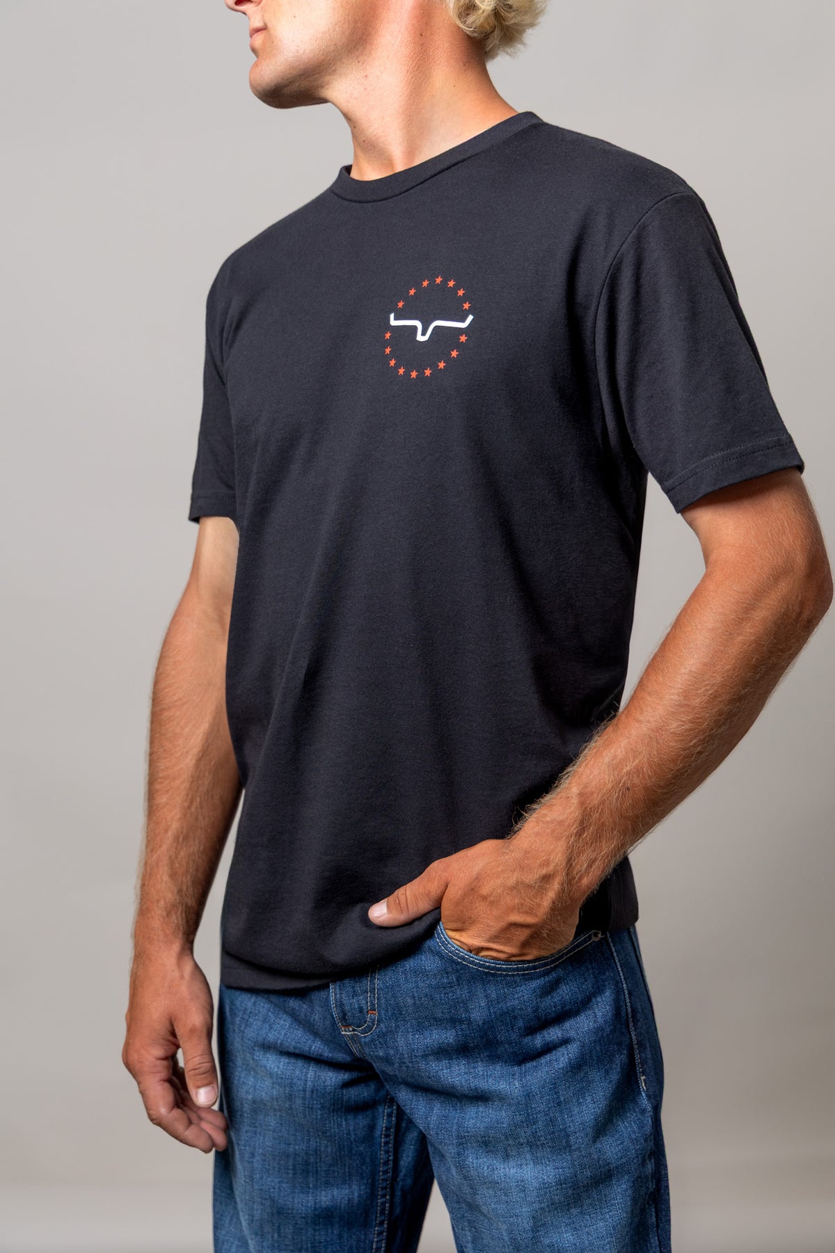 Kimes Ranch 76 short sleeve shirt in Black, side view, with a white Kimes Ranch logo surrounded by orange stars