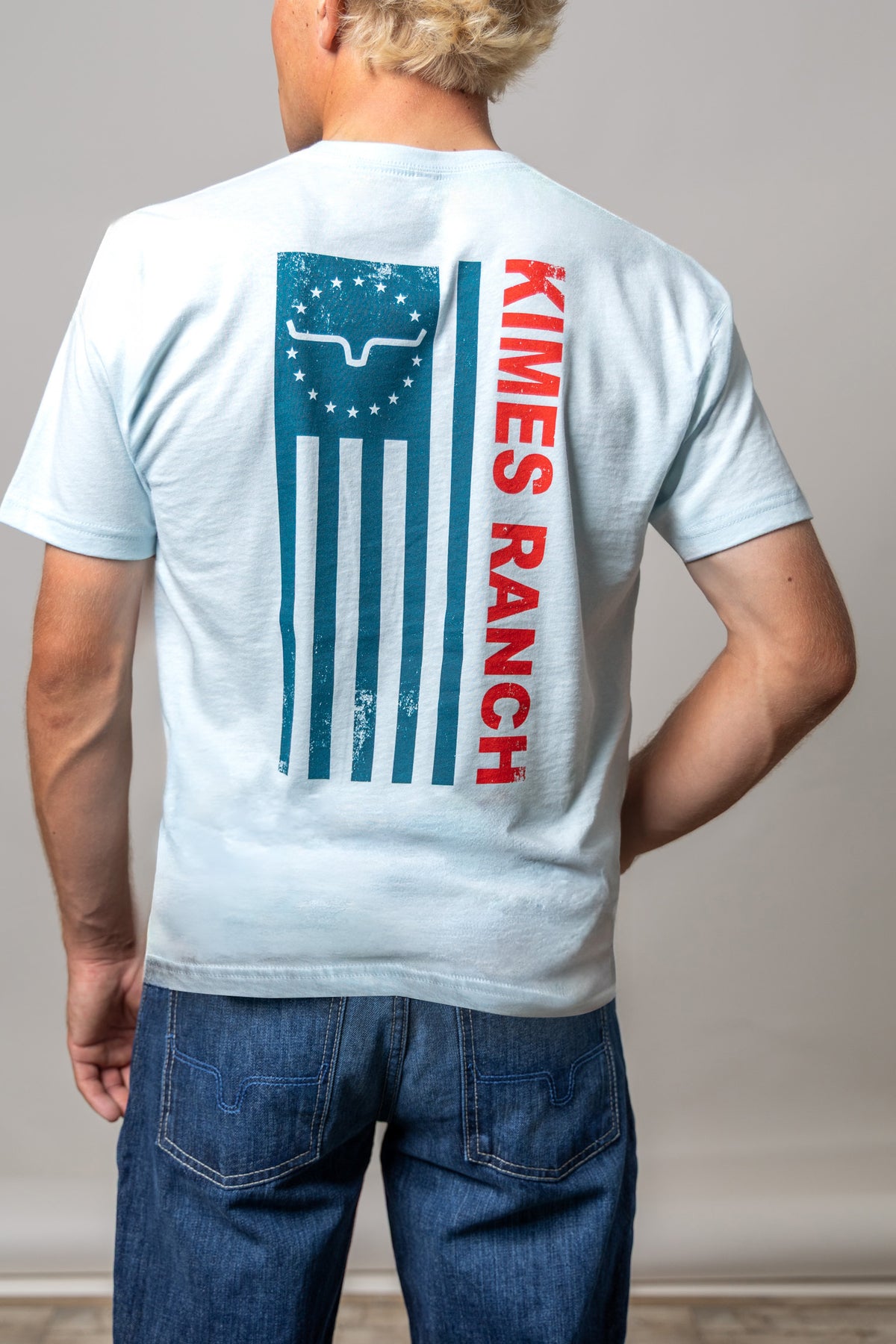 Kimes Ranch 76 shirt in Light Blue, back view, with a back graphic of a distressed flag and Kimes Ranch logo