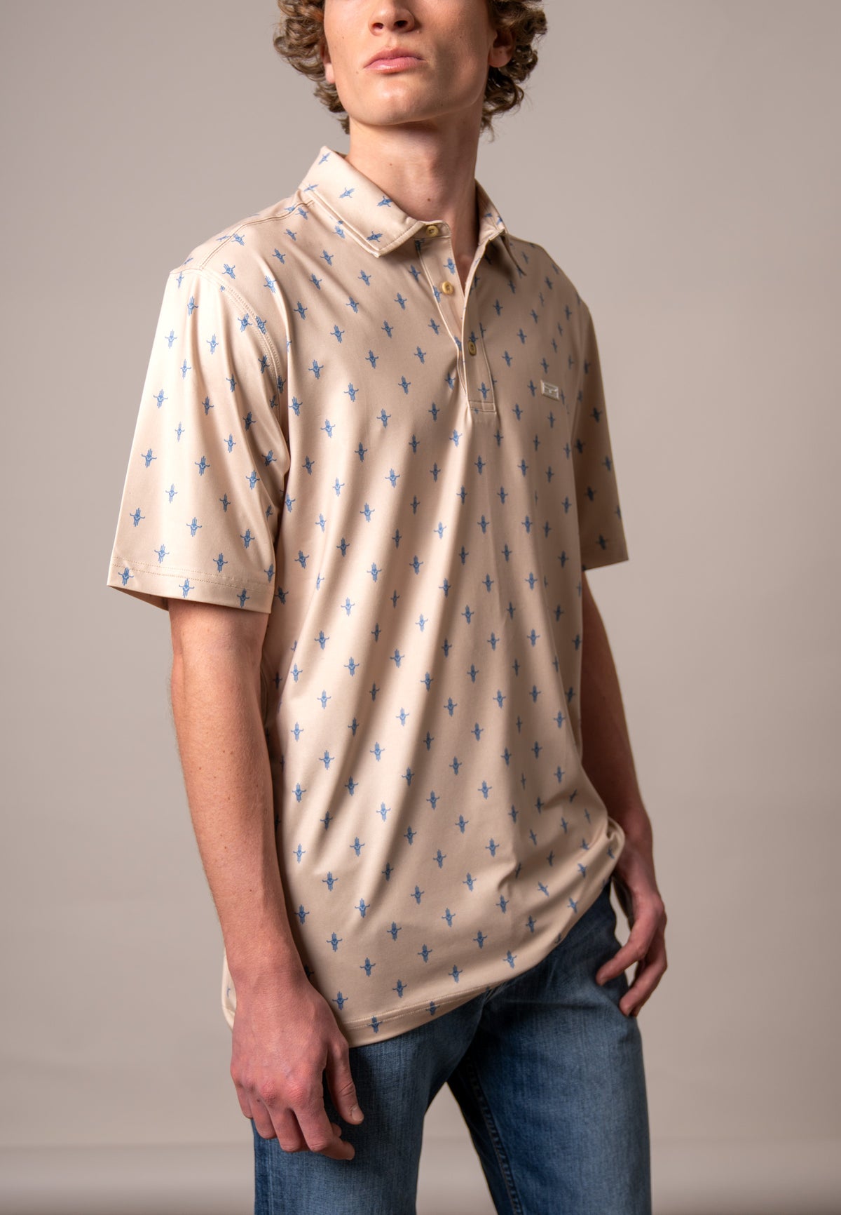 Kimes Ranch Bartram polo in Natural, side view, with an all-over blue steer logo print and a chest logo patch