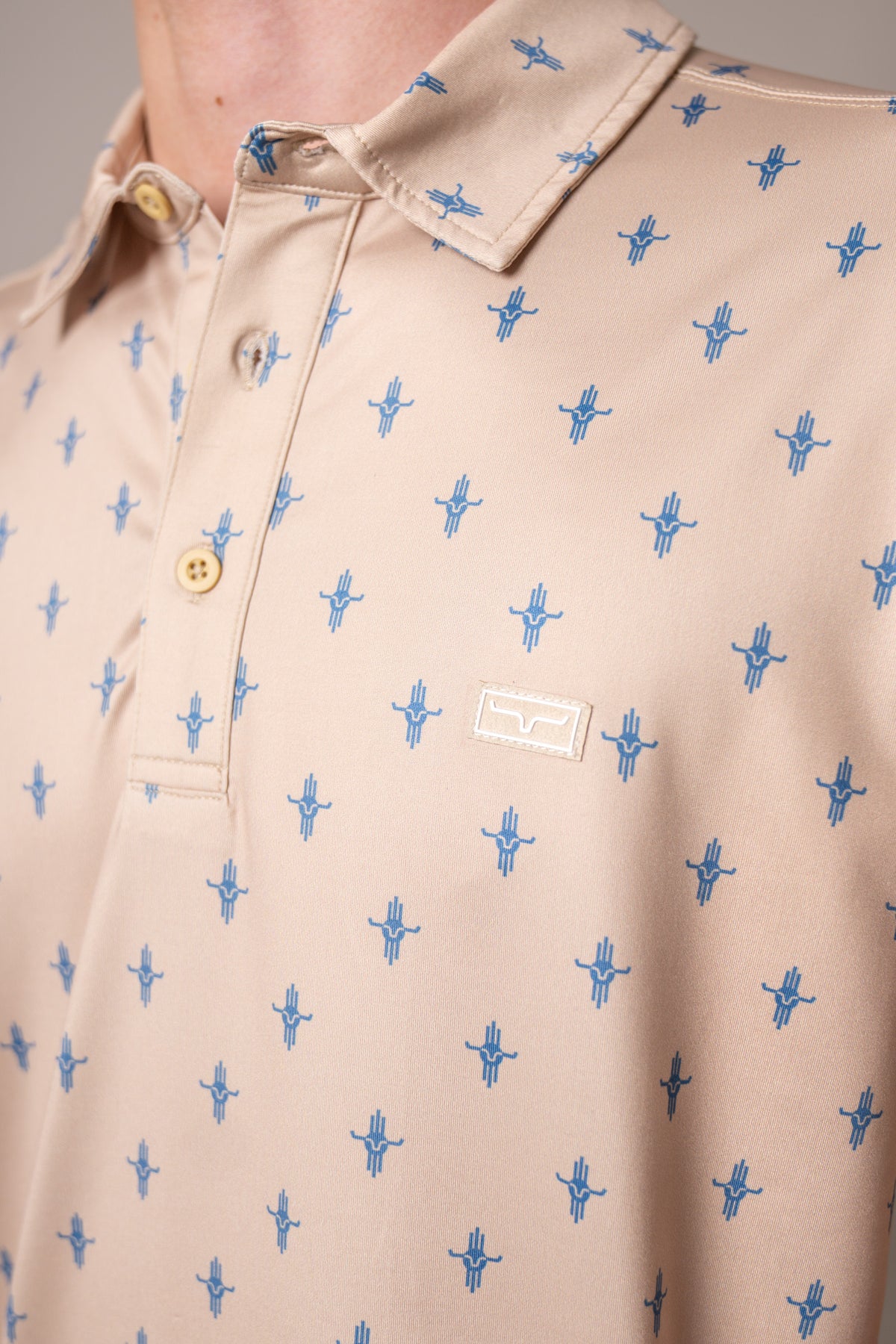 Kimes Ranch Bartram polo in Natural, close-up, with a blue steer logo print and a logo patch on the chest