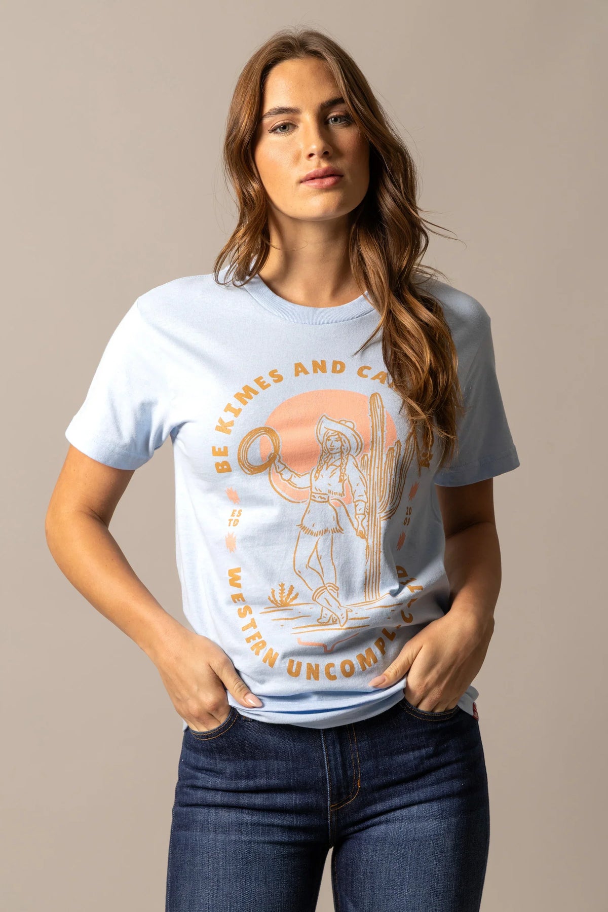 Kimes Ranch Be Kimes shirt in Baby Blue with a graphic of a cowgirl and cactus and the text Be Kimes and Calm