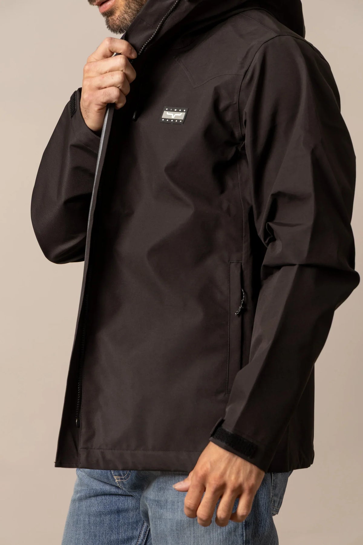 Kimes Ranch Beartooth Shell jacket in Black, side view, with a chest logo and zippered side pocket