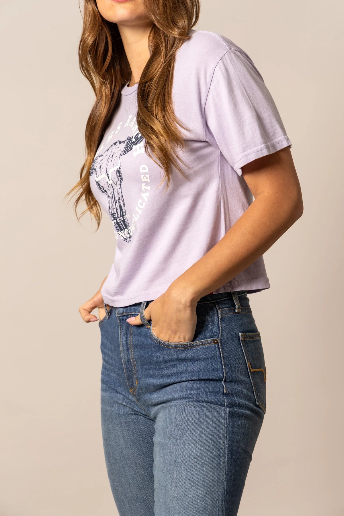 Kimes Ranch Bison Skull shirt in Lavender, side view, with a graphic of a bison skull and the text Uncomplicated