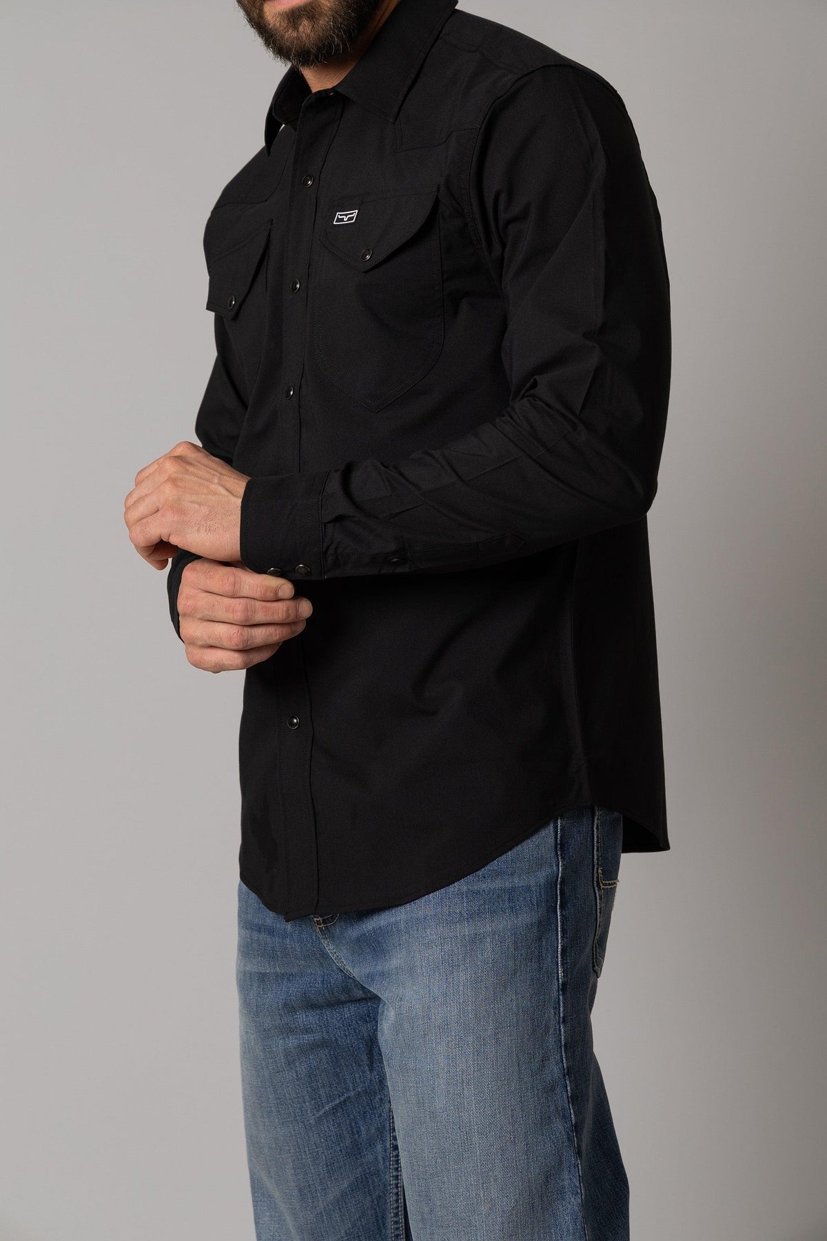 Kimes Ranch Blackout Dress Shirt in Black, side view, with chest pockets and a logo on the left pocket