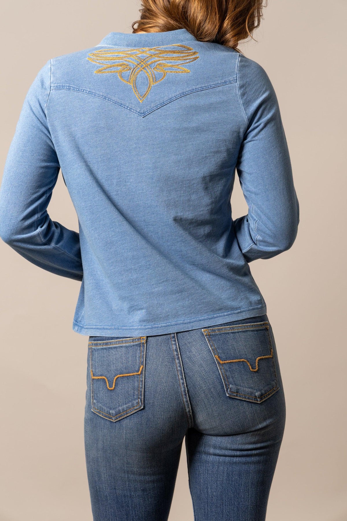 Kimes Ranch Bluebell long sleeve top in Indigo, back view, with a gold embroidered logo on the back yoke