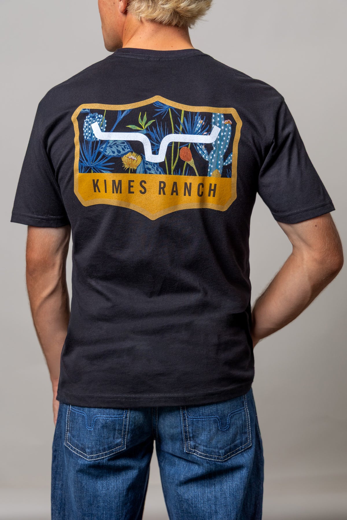 Kimes Ranch Dillard Floral shirt in Black, back view, with a back graphic of blue desert plants and the Kimes Ranch logo