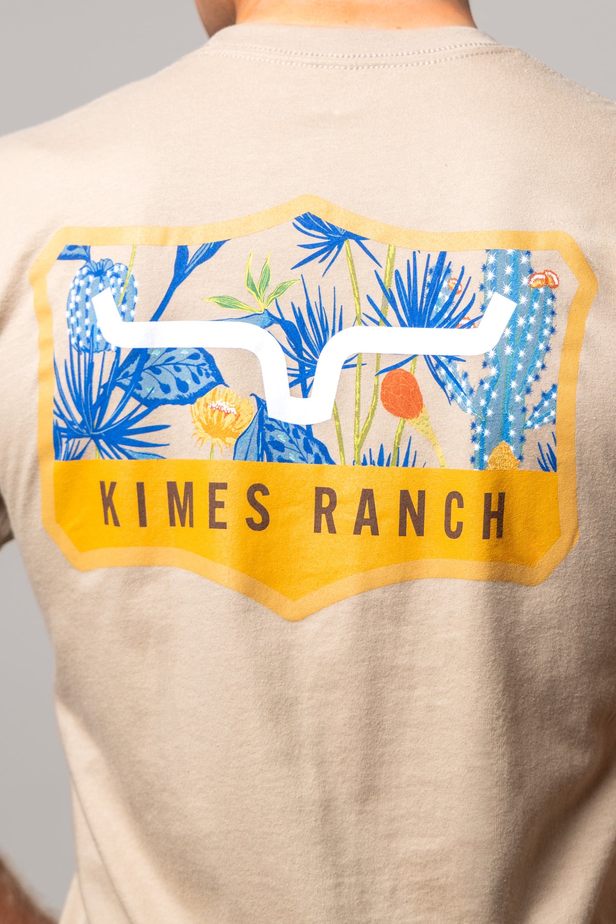 Kimes Ranch Dillard Floral, back view, shirt back with shield graphic of blue cacti and yellow flowers