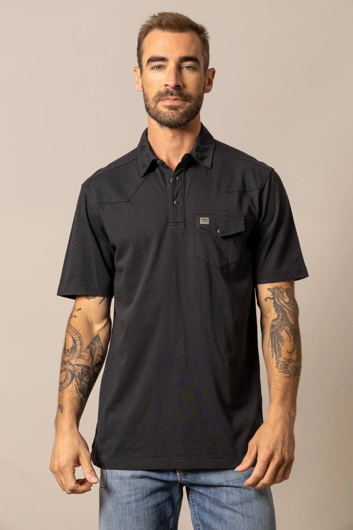 Kimes Ranch Fluger Polo in Black with a collar, short sleeves, and a chest pocket with a logo