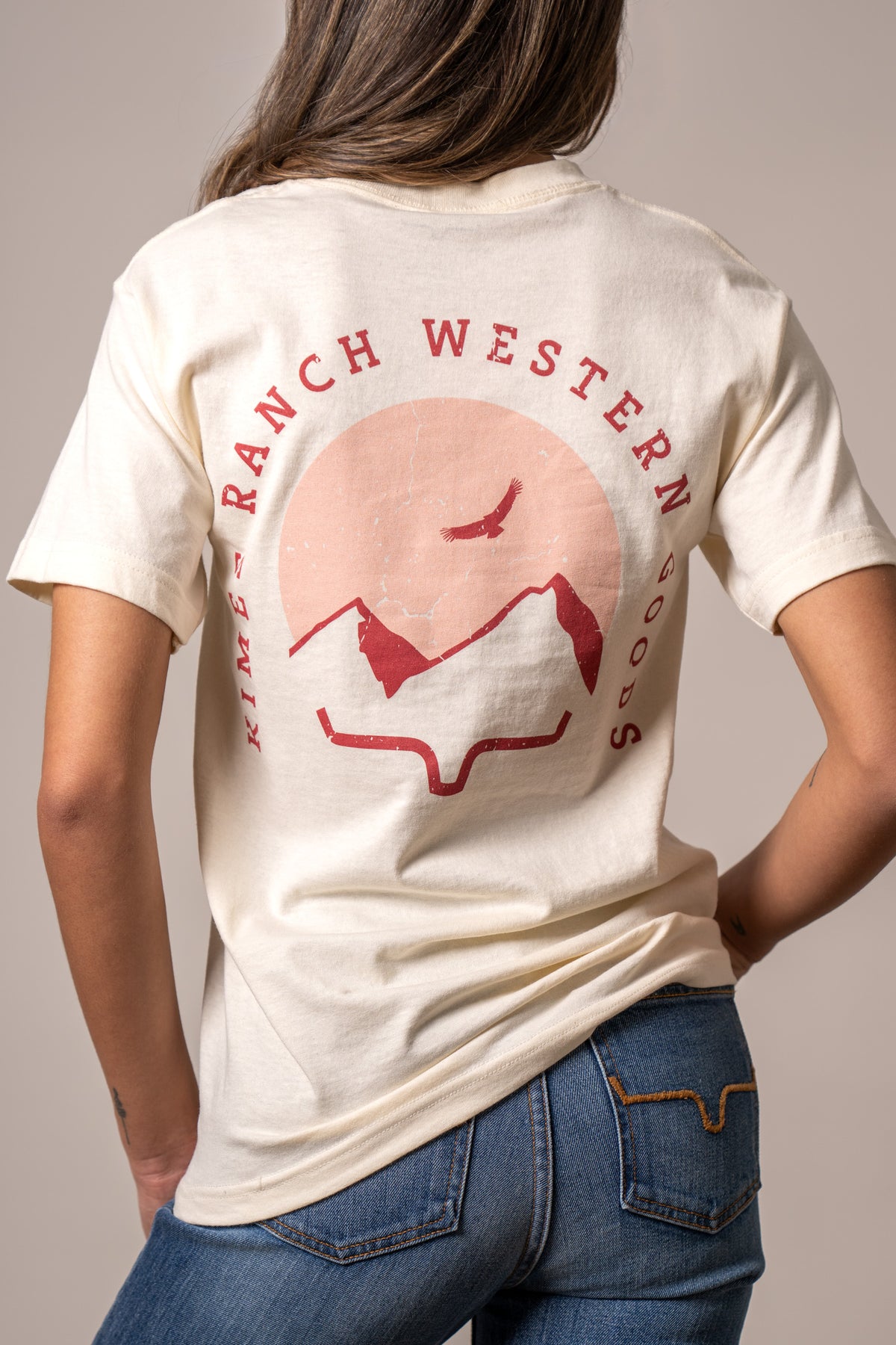 Kimes Ranch Flying High, back view, Cream shirt with a back graphic of mountains