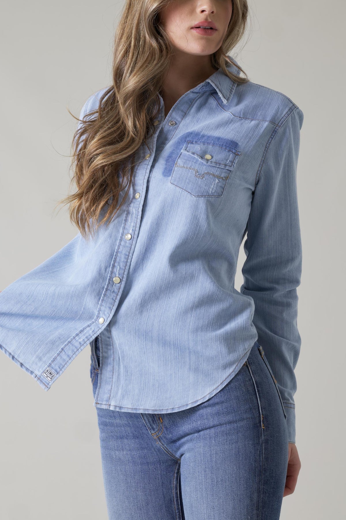Kimes Ranch Kaycee Denim Top in blue with a distressed chest pocket and long sleeves
