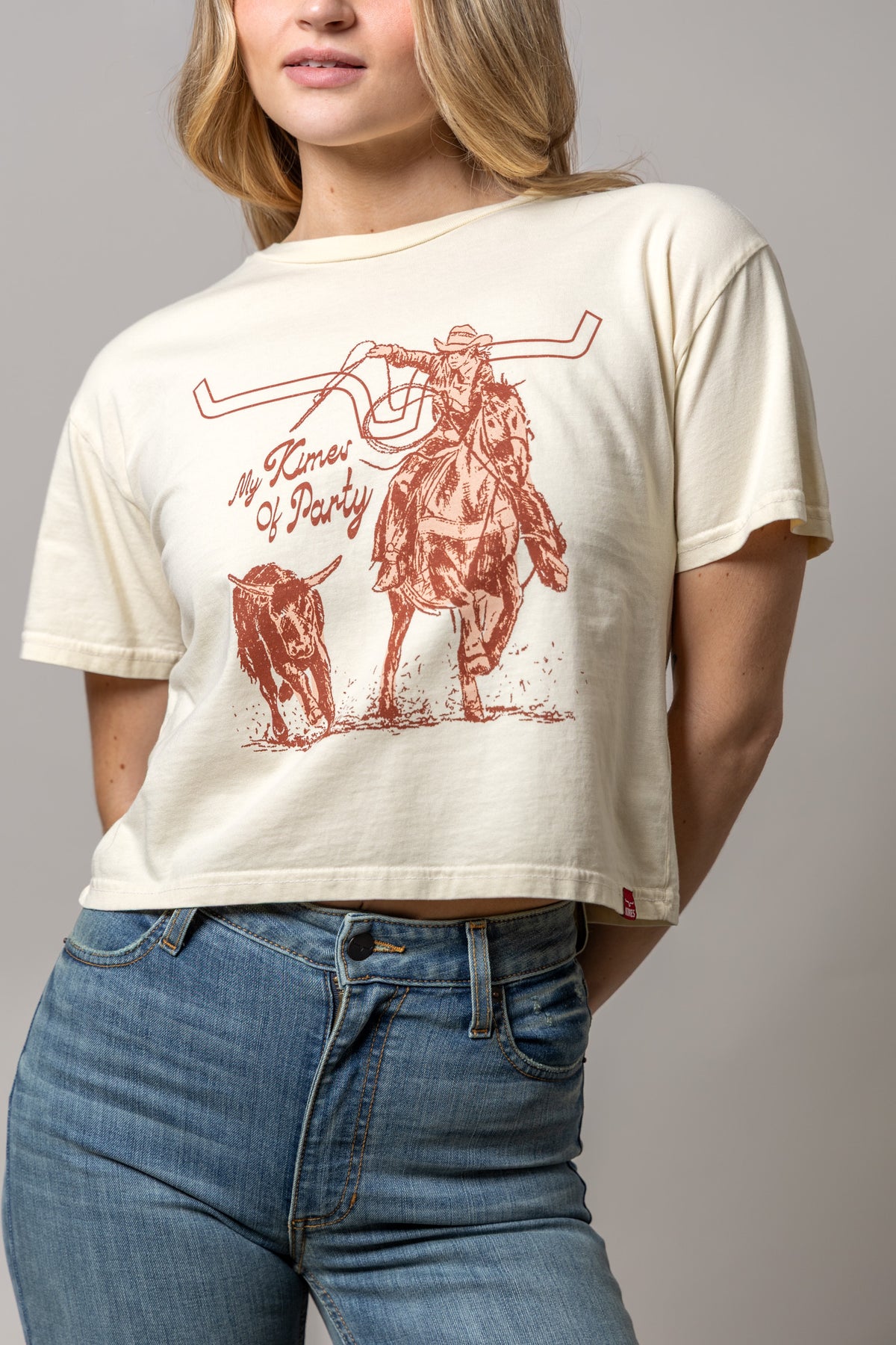 Kimes Of A Party shirt in Ivory with a graphic of a cowboy on horseback with a bull and the text My Kimes Of Party