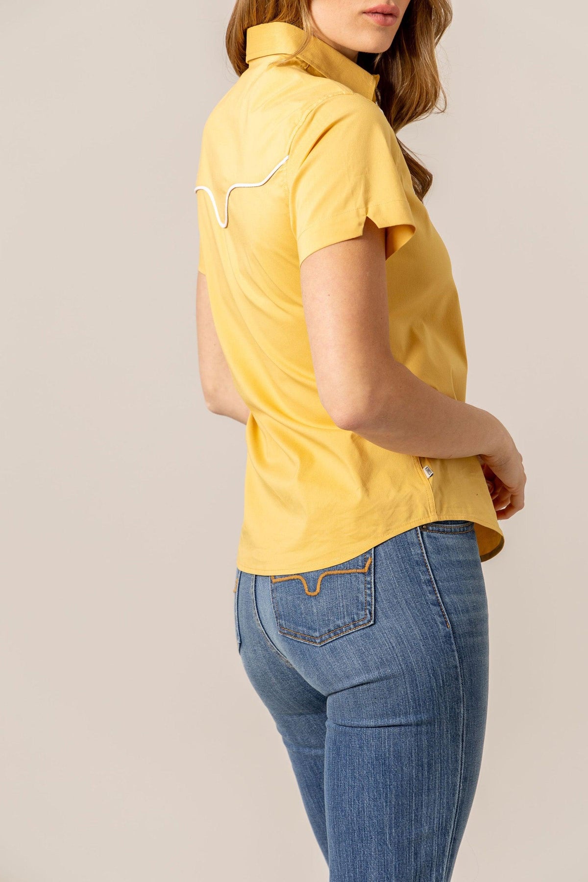Kimes Ranch Logo Horn Snap top in Gold, side view, with short sleeves and white piping on the back yoke