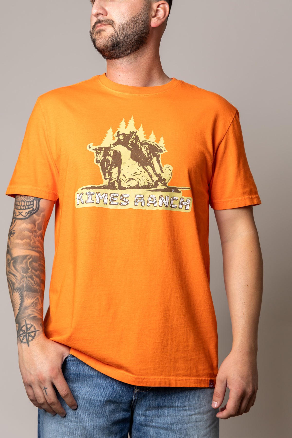 Kimes Ranch Lucky B Bull Dogger shirt in Vintage Orange with a graphic of a cowboy on a bull and the Kimes Ranch logo
