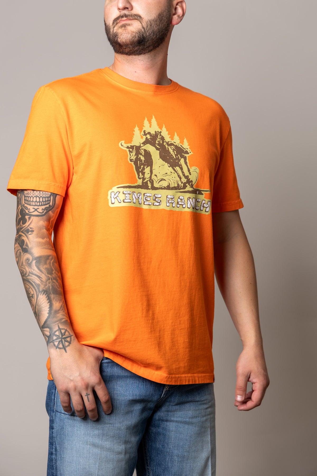 Kimes Ranch Lucky B Bull Dogger shirt in Vintage Orange with a graphic of a cowboy on a bucking bull and the Kimes Ranch logo