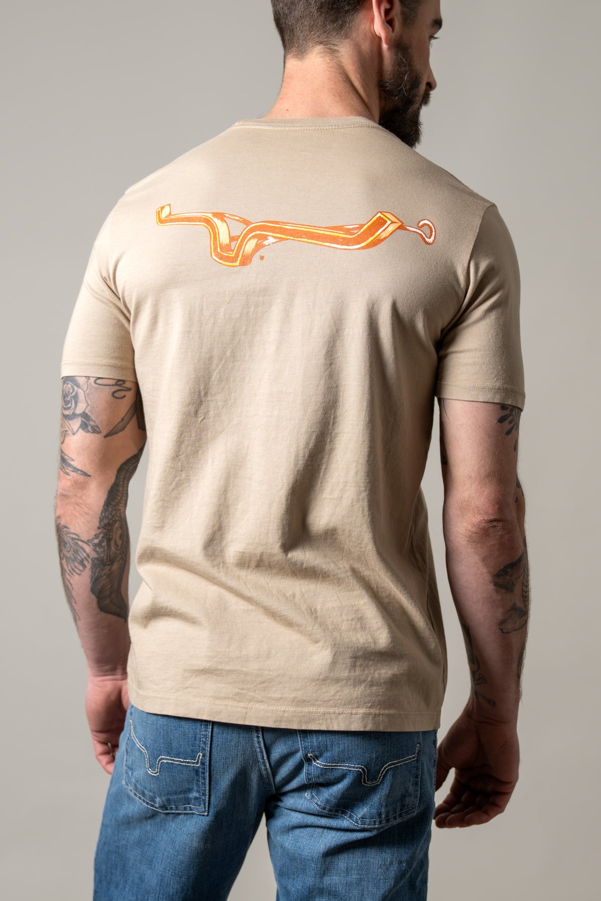 Kimes Ranch Lucky B Iron shirt in Sand, back view, with a back graphic of an orange horseshoe