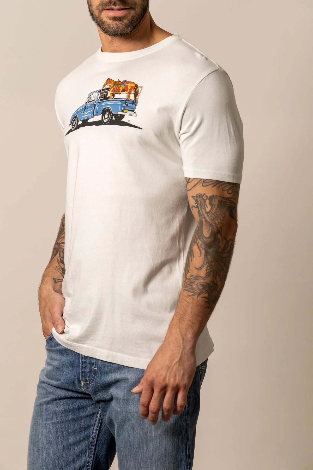 Kimes Ranch Lucky B Truck shirt in Natural, side view, with a graphic of a blue truck carrying a horse