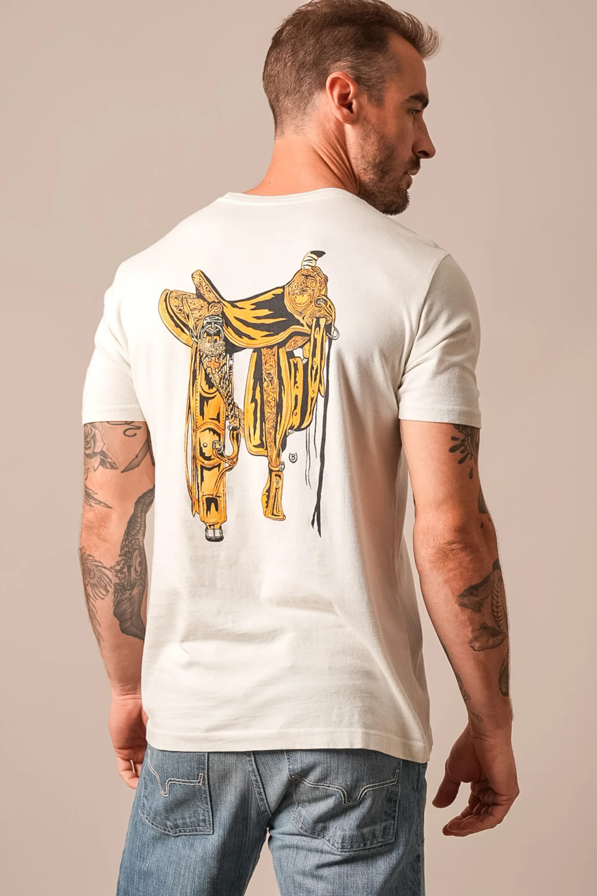 Kimes Ranch Lucky B Saddle shirt in Natural, back view, with a large gold and black saddle graphic on the back