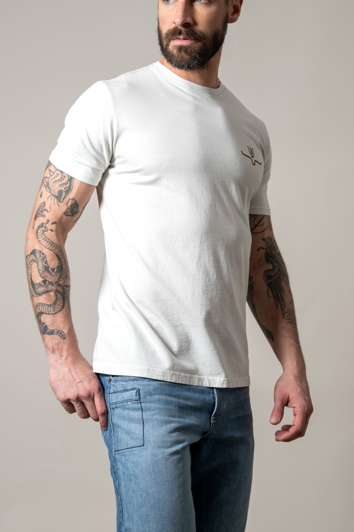 Kimes Ranch Lucky B Tuned shirt in Natural, side view, with short sleeves and a crew neck with a small logo on the chest