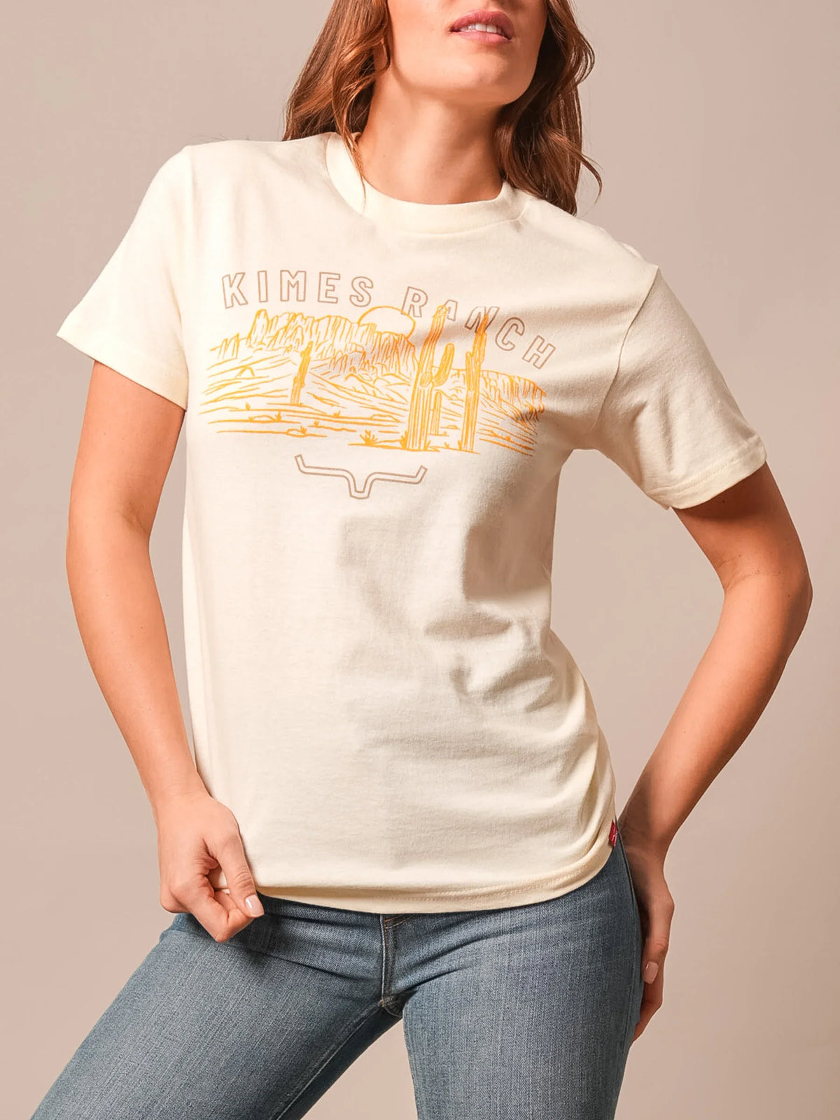 Kimes Ranch Mountain Badge Cream t-shirt with a desert landscape graphic and the Kimes Ranch logo