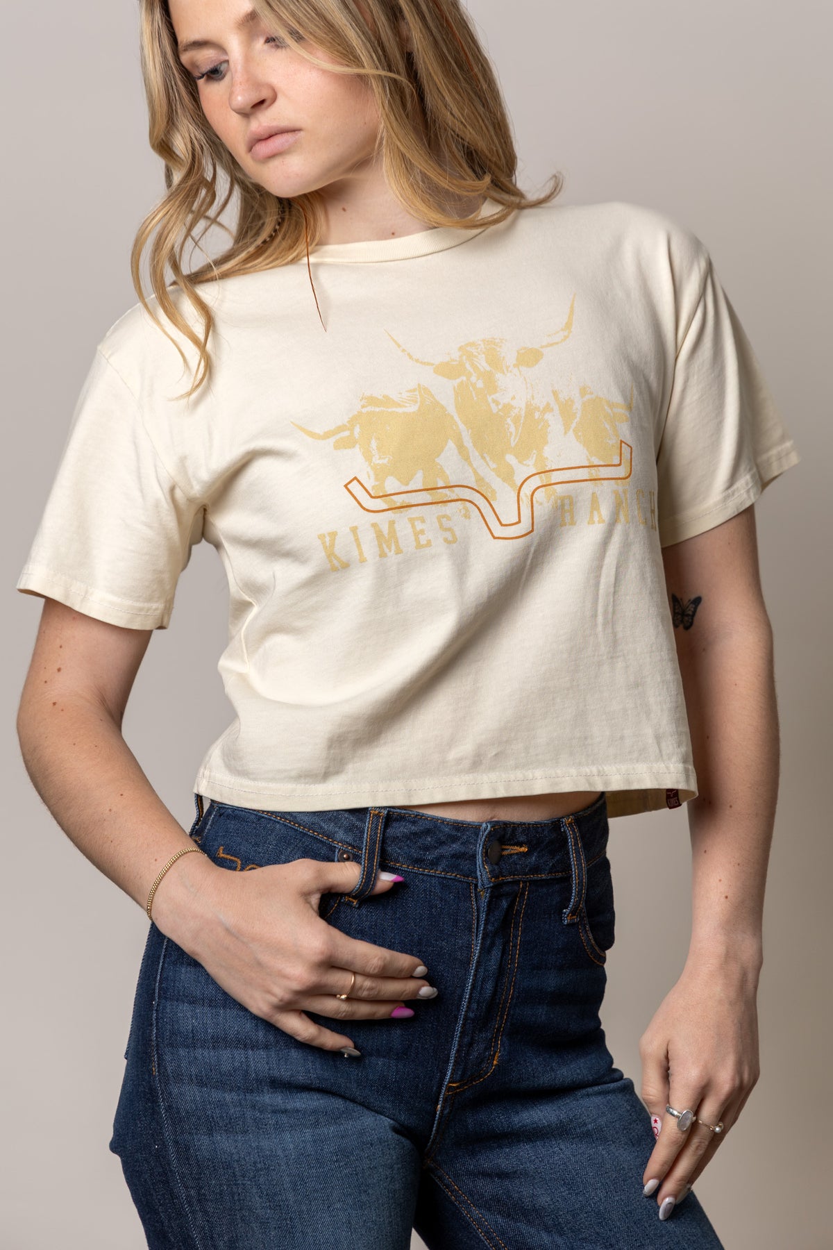 Kimes Ranch Movin' Out shirt in Ivory with a graphic of longhorns and the Kimes Ranch logo