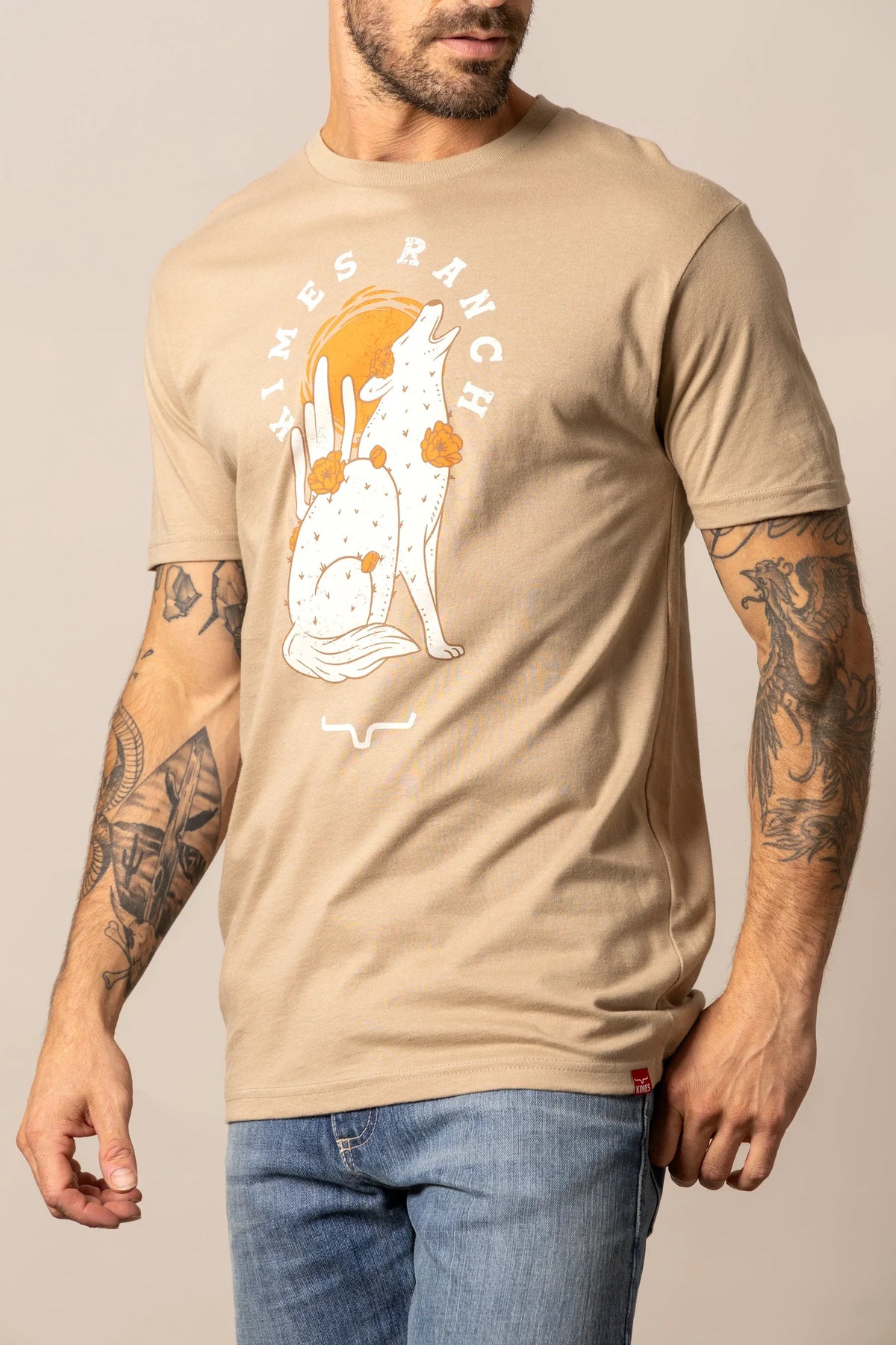 Kimes Ranch Night Call Tan short sleeve shirt with a howling coyote and cactus graphic and Kimes Ranch logo
