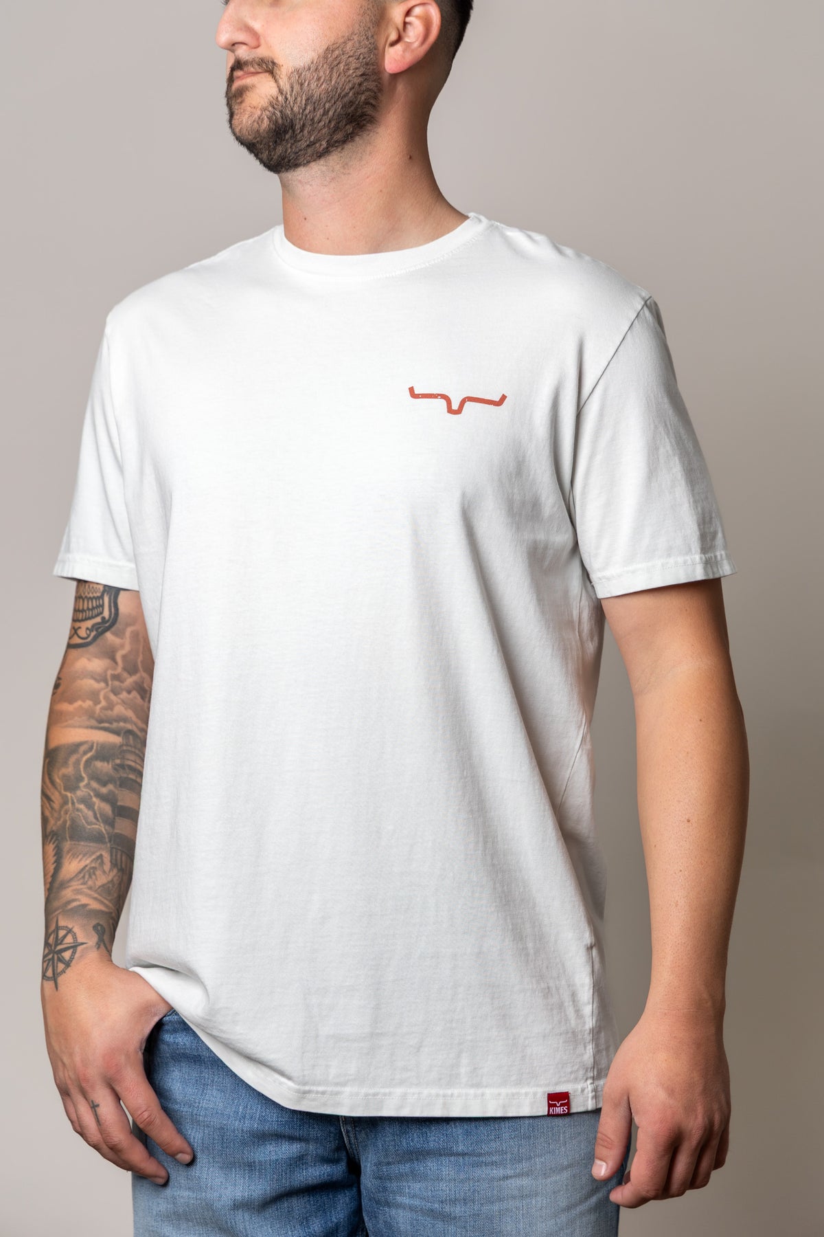 Kimes Ranch Not Our First shirt in Muted White with a small orange logo on the chest