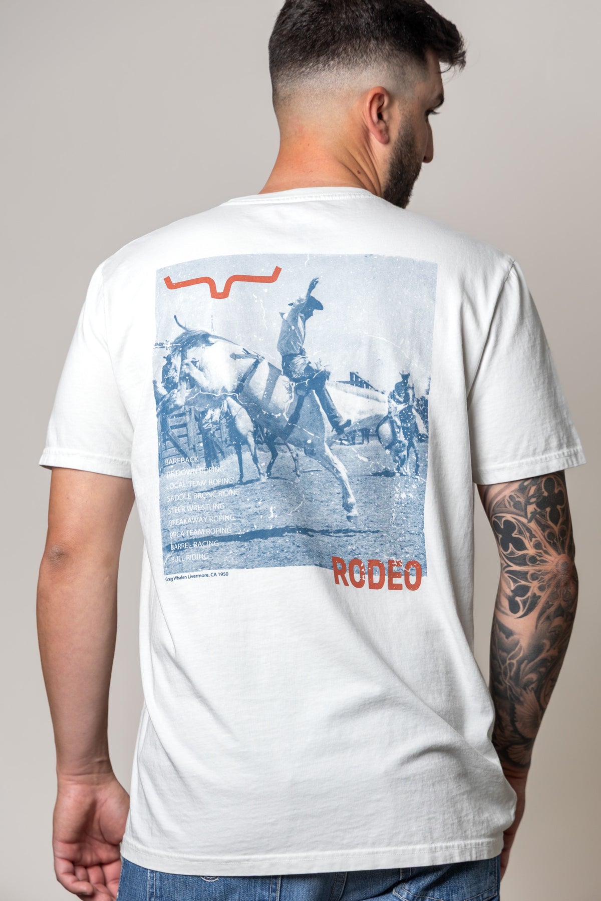 Kimes Ranch Not Our First shirt in Muted White, back view, with a back graphic of a rodeo scene and the word RODEO