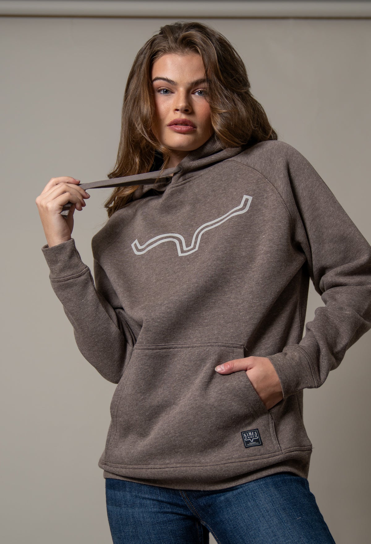 Kimes Ranch Ladies Outlier Hoodie in Dark Brown with a white outline graphic and front kangaroo pocket