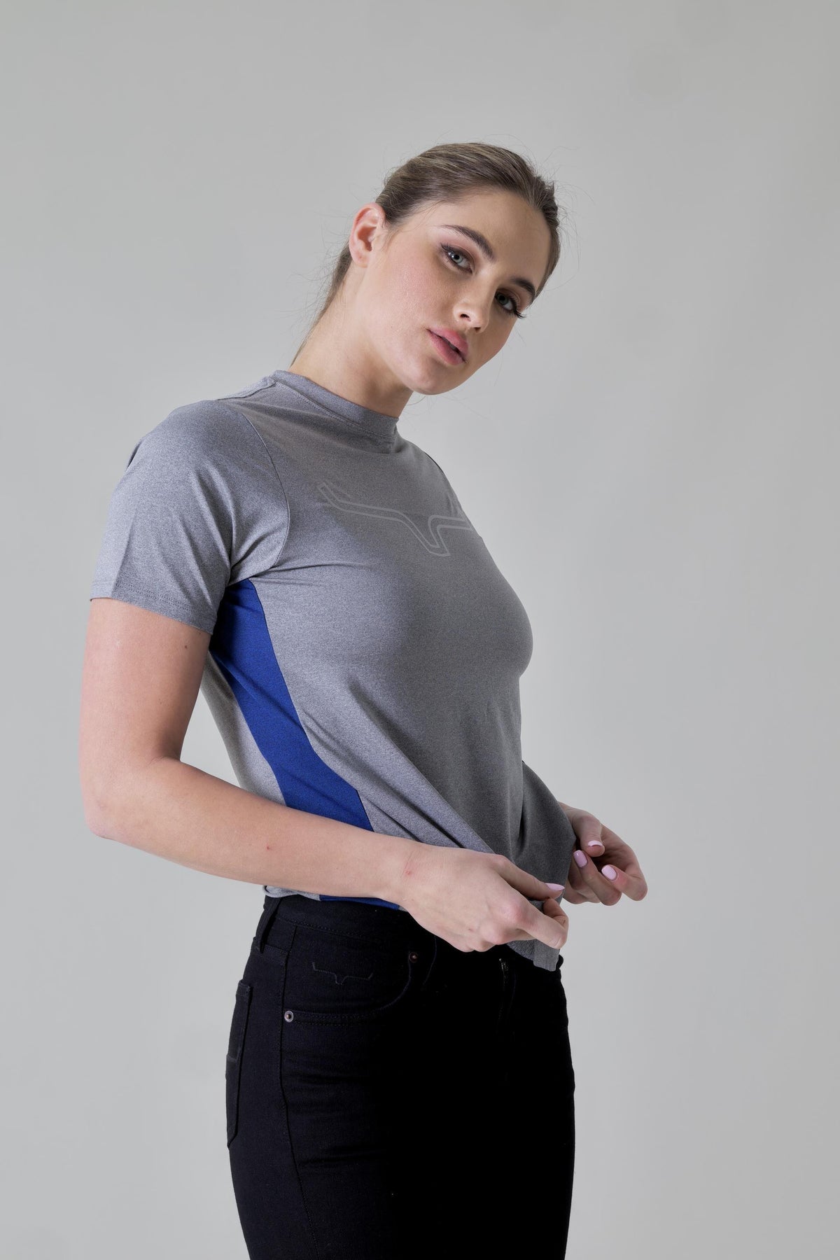 Kimes Ranch Ladies Phase 2 Tech Shirt in Grey Heather, side view, with blue side panels and a subtle logo on the chest