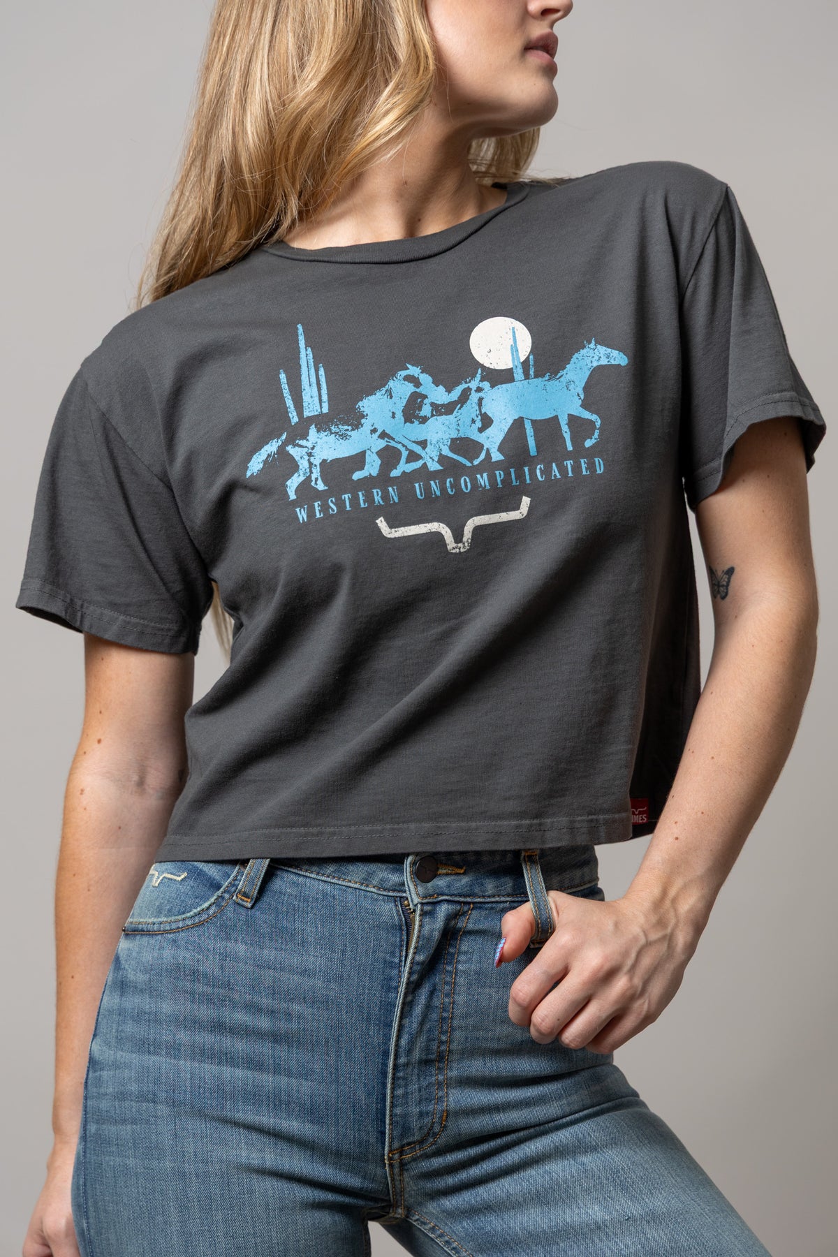 Kimes Ranch Plains Stampede shirt in Pepper with a blue graphic of horses and the text Western Uncomplicated