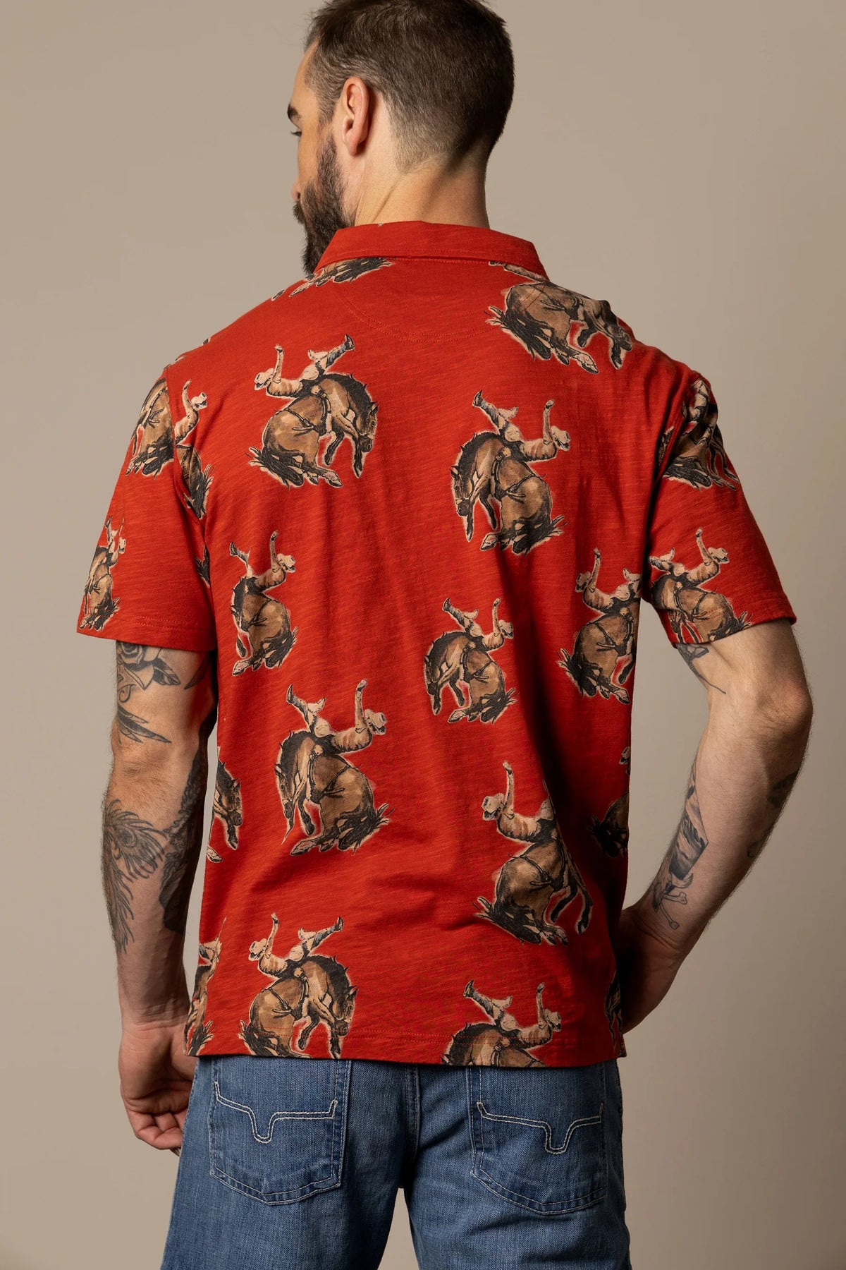 Kimes Ranch RP Winning Ride Polo in Brick Red, back view, with an all-over print of a cowboy riding a bucking horse