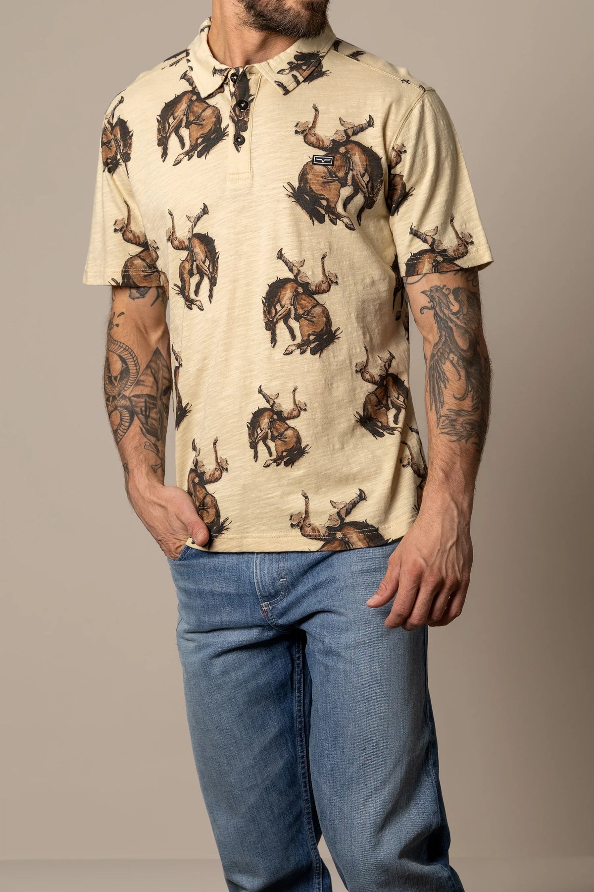 Kimes Ranch RP Winning Ride Polo in Tan with a repeating print of a cowboy riding a bucking horse