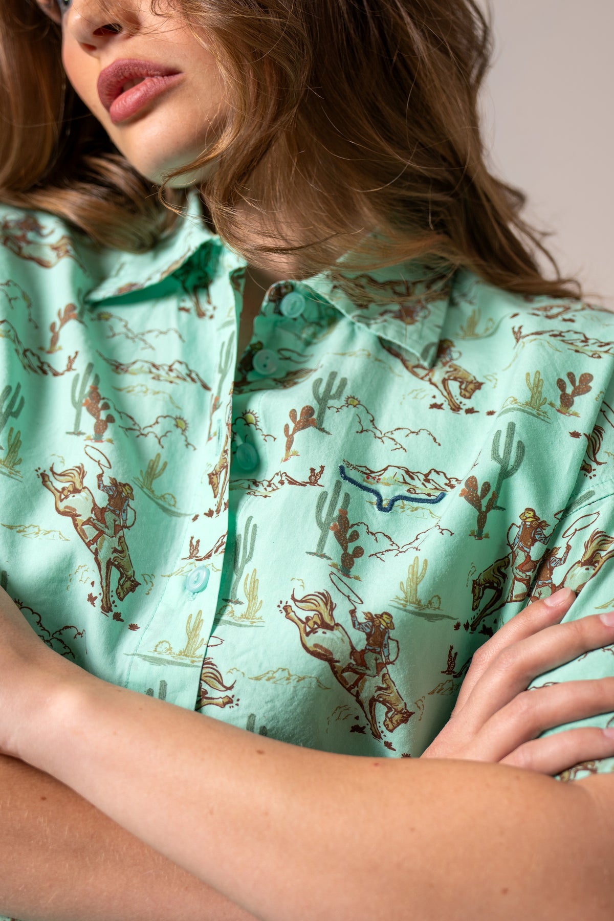 Kimes Ranch Ranchero top in Turquoise, close-up, with a western print of cowboys and cacti and a chest pocket