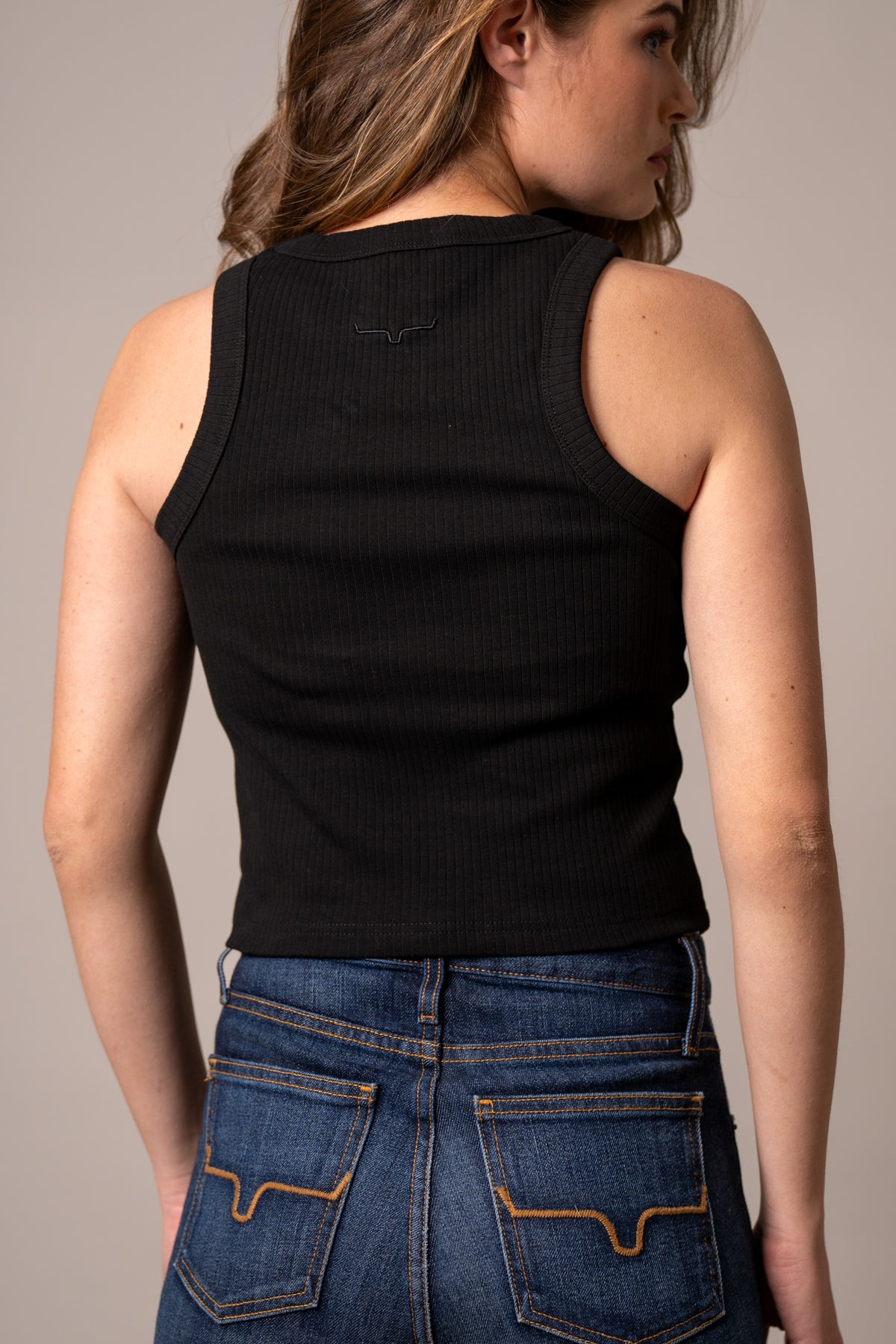 Kimes Ranch Reagan, back view, Black ribbed tank top with a small embroidered logo at the back yoke
