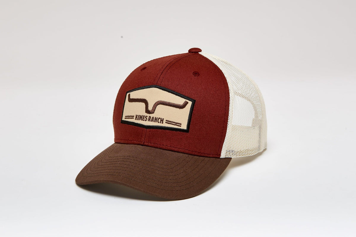 Kimes Ranch Replay Trucker Hat in Rusty, side view, with a front embroidered logo and mesh back