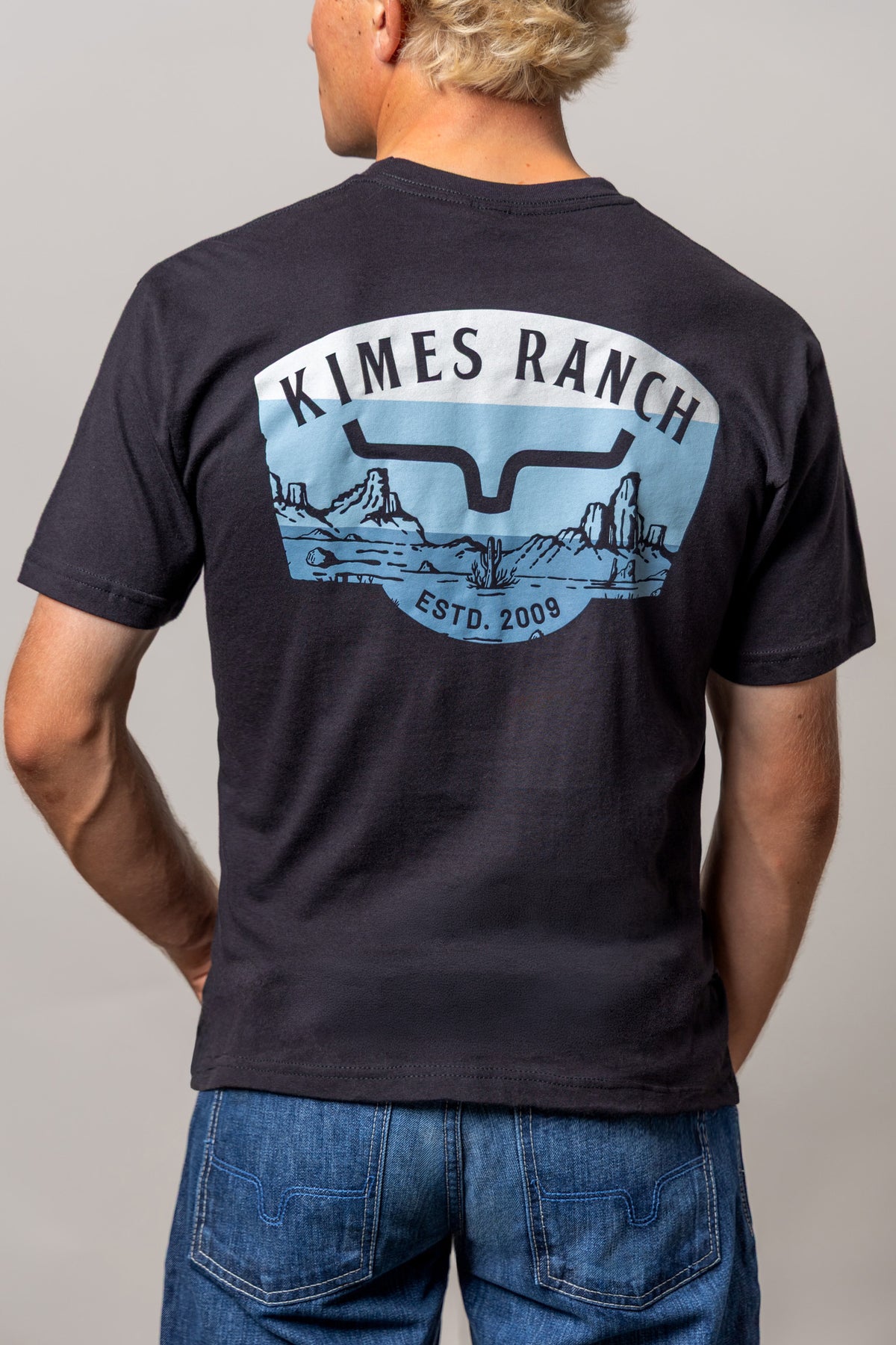 Kimes Ranch Southwestern shirt in Black, back view, with a back graphic of a desert landscape and the Kimes Ranch logo