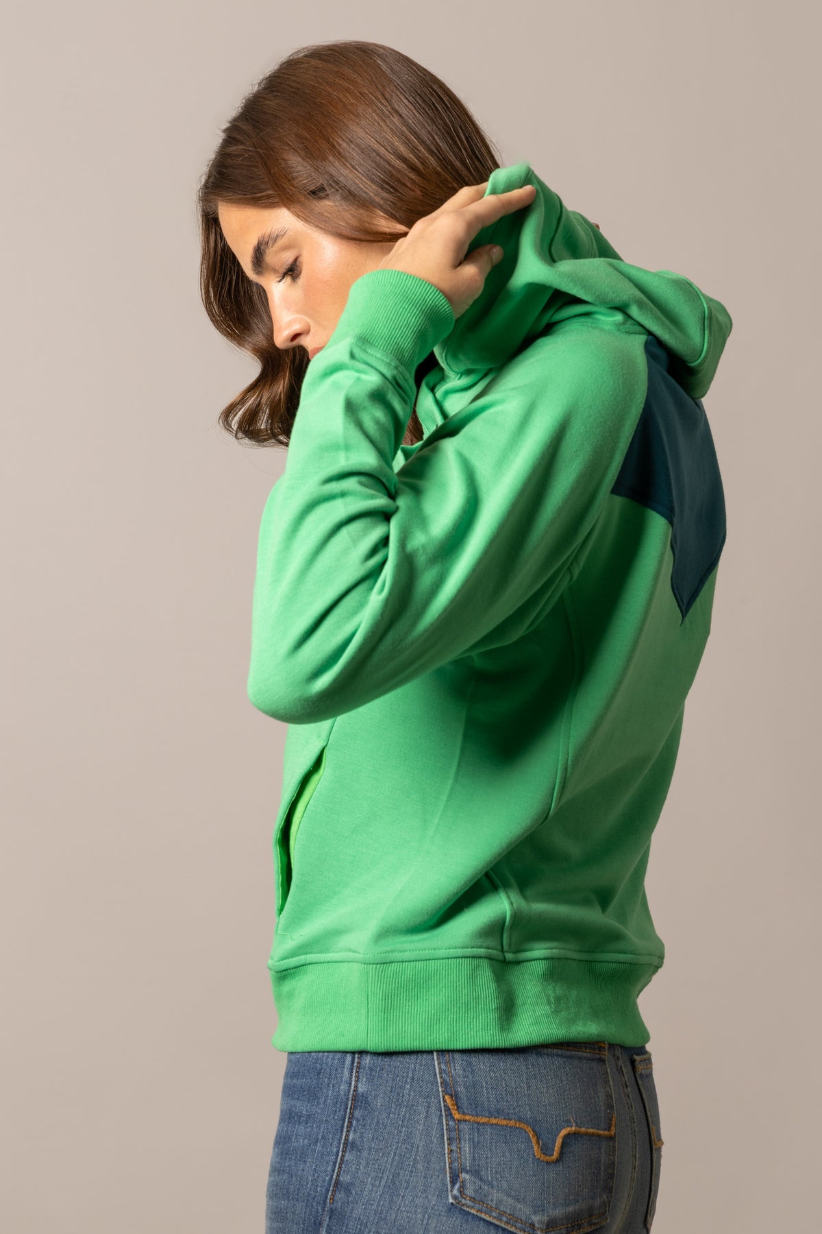 Kimes Ranch Stella hoodie in Kelly Green, side view, with a navy shoulder panel and ribbed cuffs
