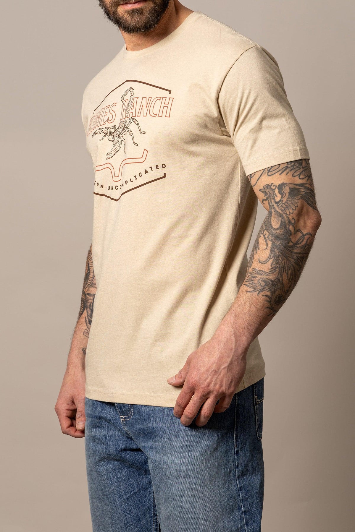 Kimes Ranch Sting shirt in Cream, side view, with a scorpion graphic and Western Uncomplicated text