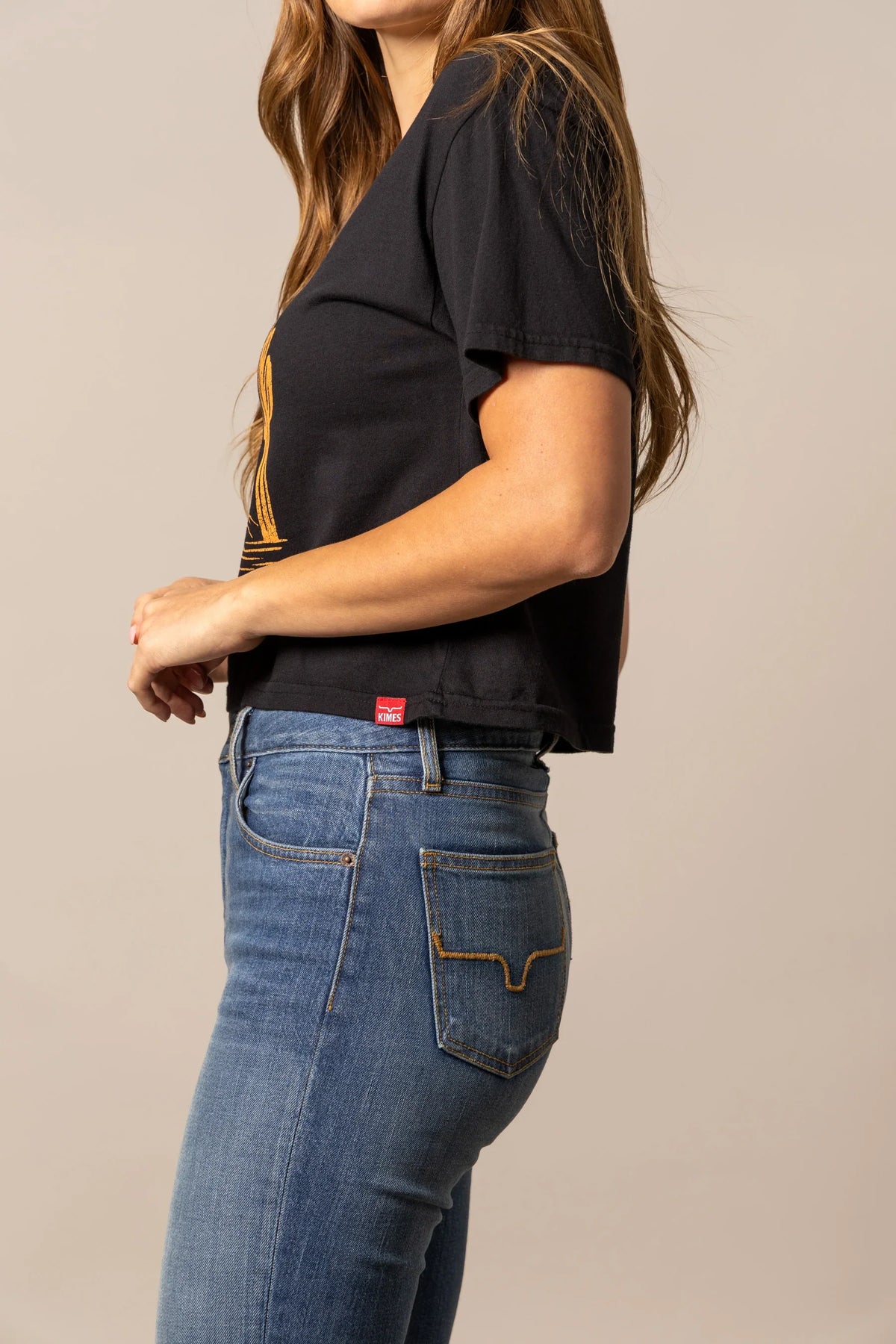 Kimes Ranch The Road, side view, Black short sleeve shirt with the red brand tag at the hem