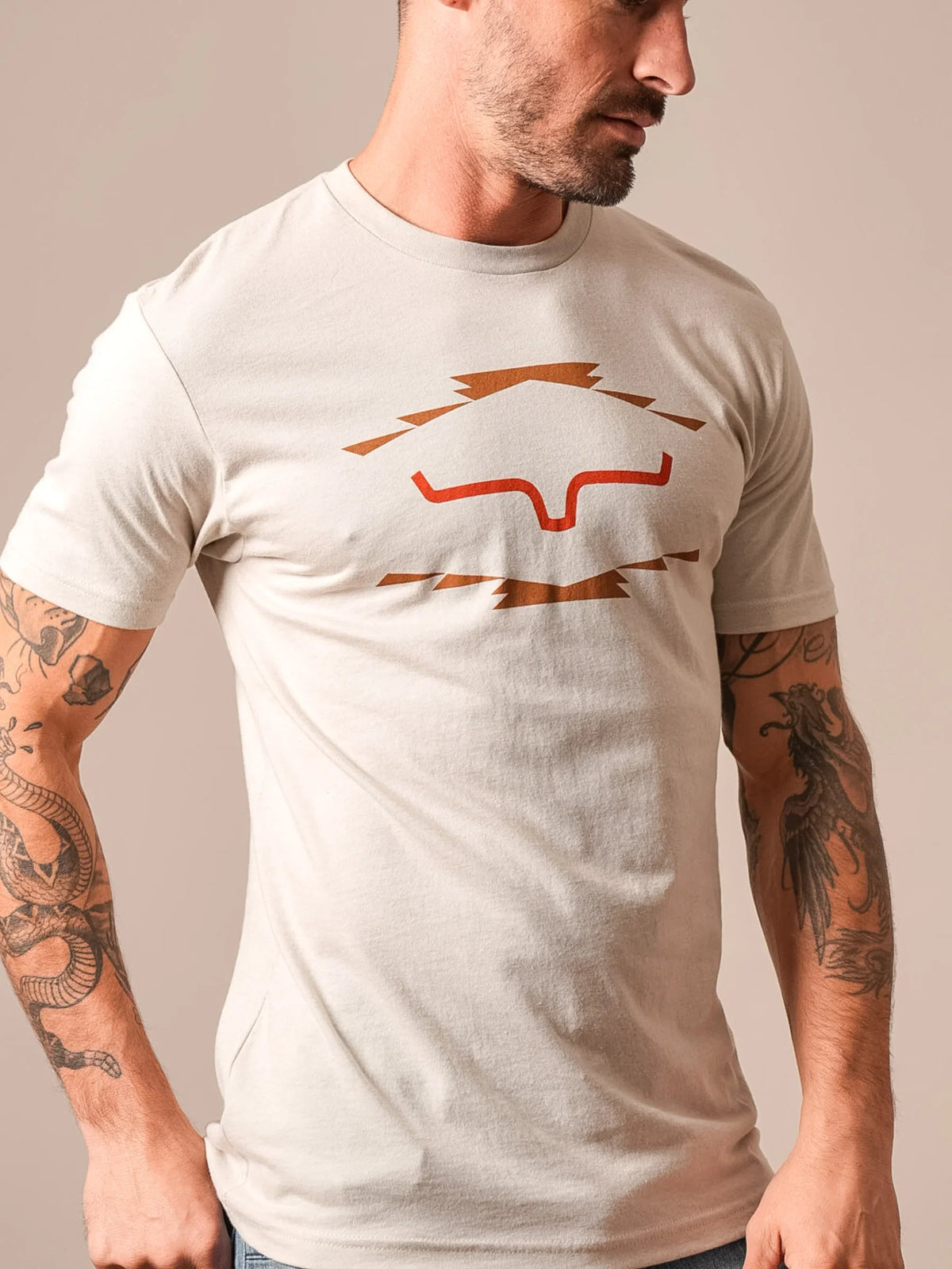 Kimes Ranch Vintage Badge shirt in Sand with a stylized steer logo graphic on the chest