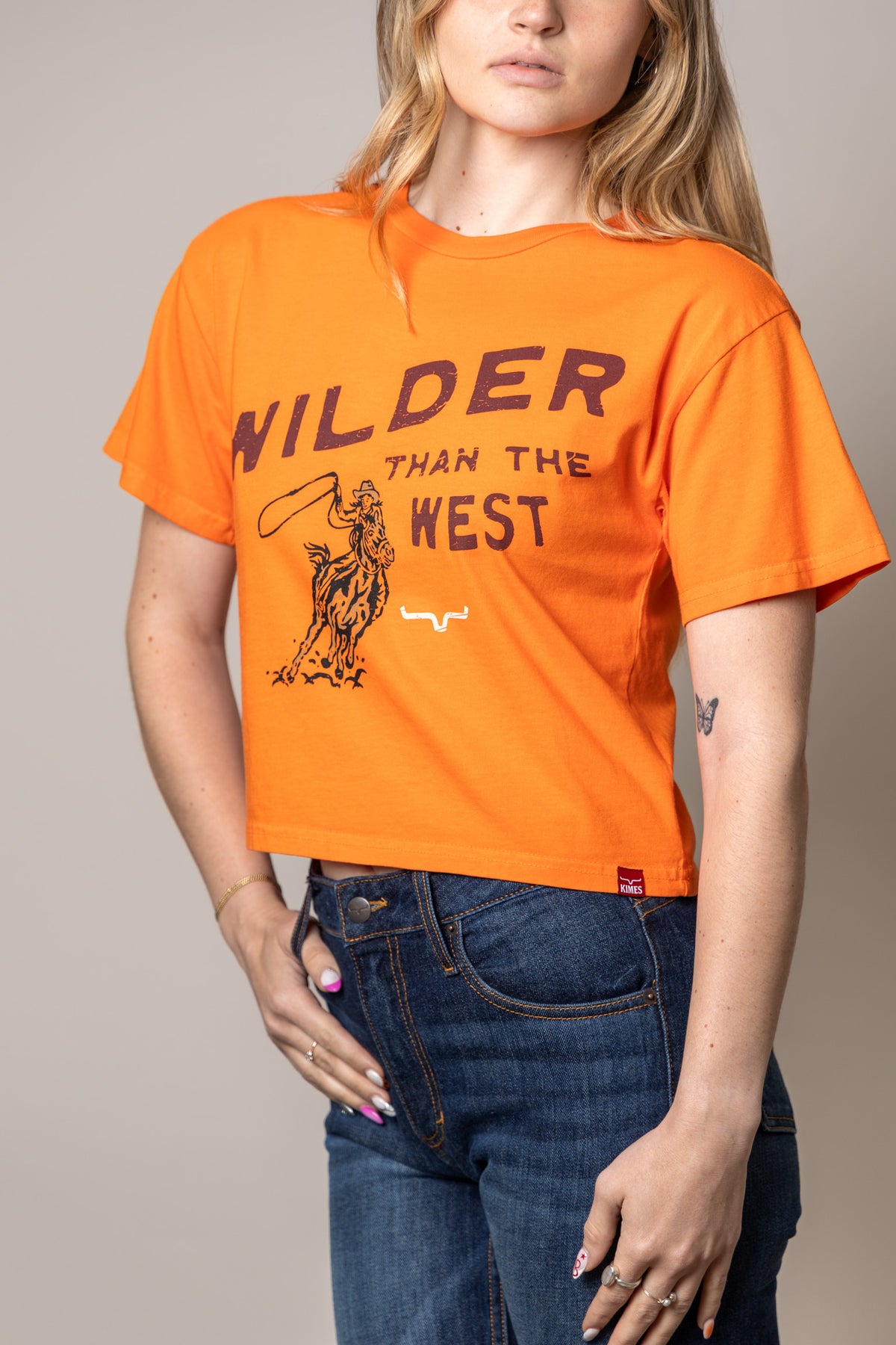 Kimes Ranch Wilder Than The West Vintage Orange shirt with a cowboy graphic and text