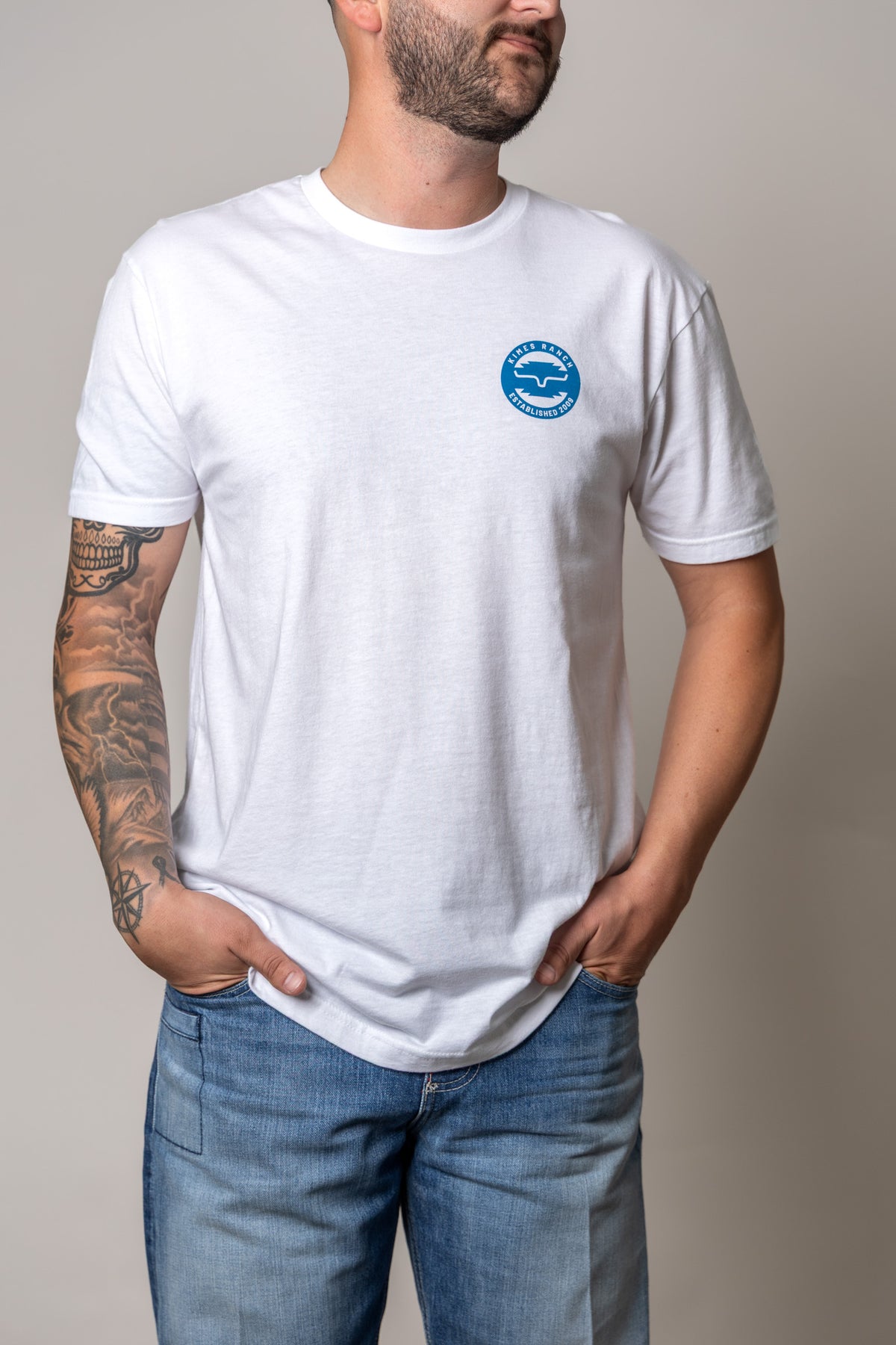 Kimes Ranch Wood Stamp White short sleeve t-shirt with a blue circular Kimes Ranch logo on the chest