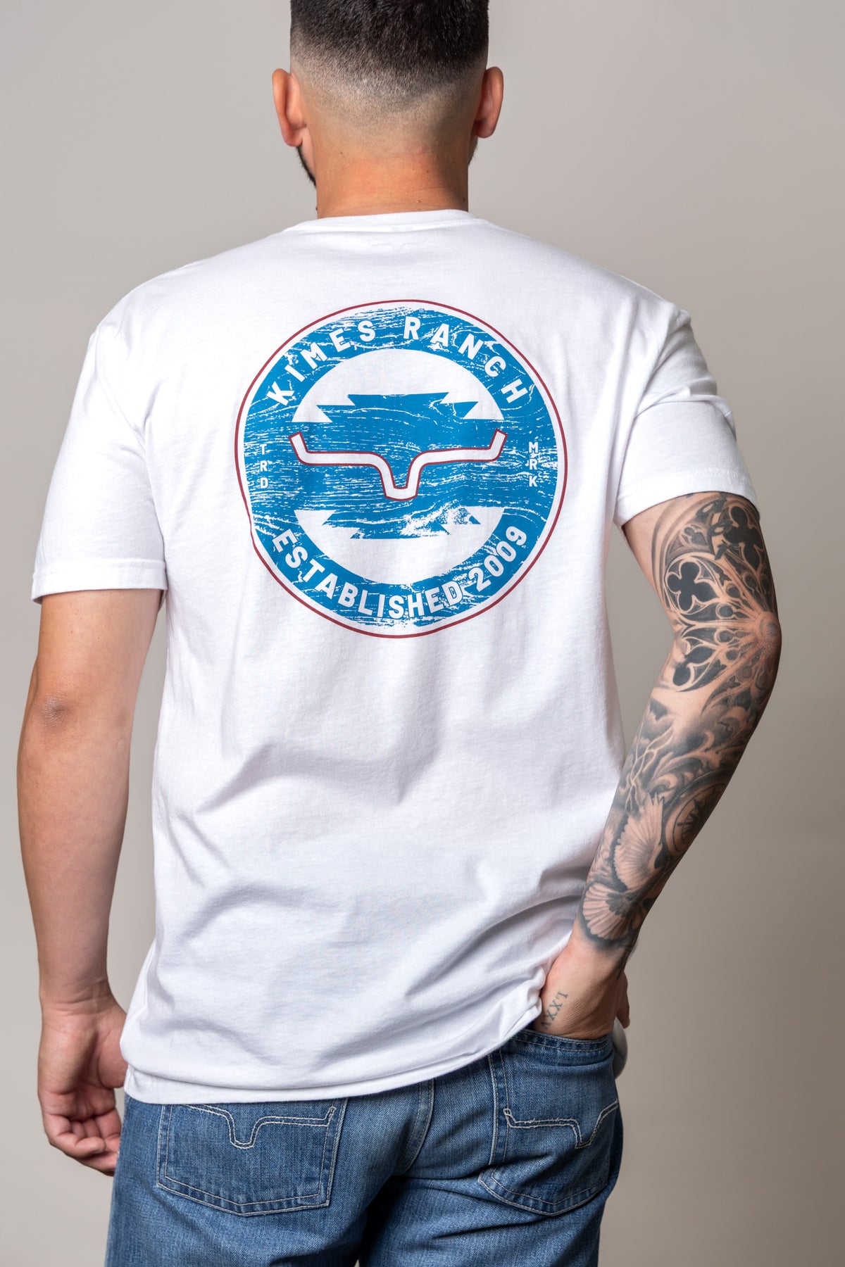 Kimes Ranch Wood Stamp, back view, shirt back with large blue and red circular logo featuring the Kimes Ranch logo