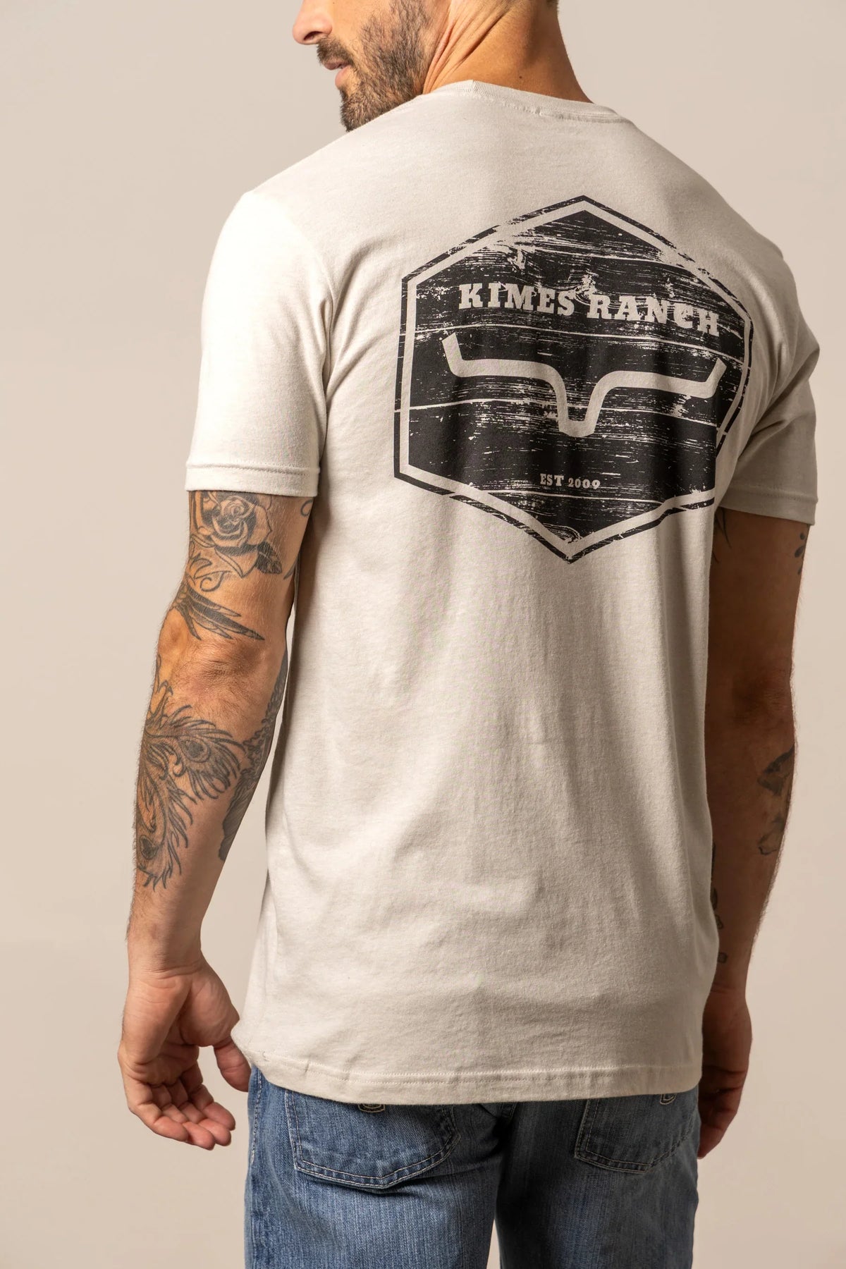 Kimes Ranch Wooden Hex shirt in Sand, back view, with a back graphic featuring the Kimes Ranch logo and EST 2009 text