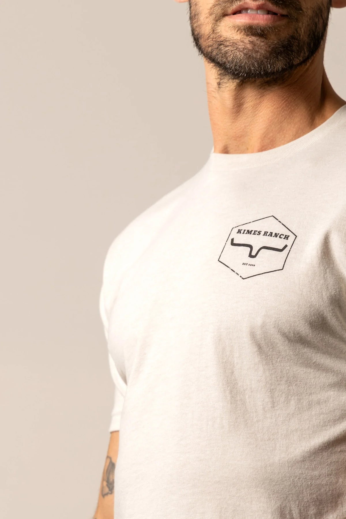 Kimes Ranch Wooden Hex shirt in Sand with a close-up of the chest logo