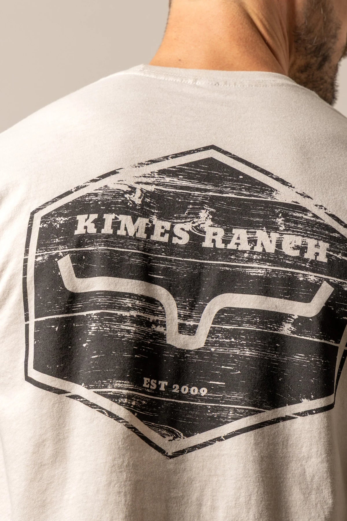 Kimes Ranch Wooden Hex shirt in Sand, back view, with a distressed hexagon graphic featuring the Kimes Ranch logo