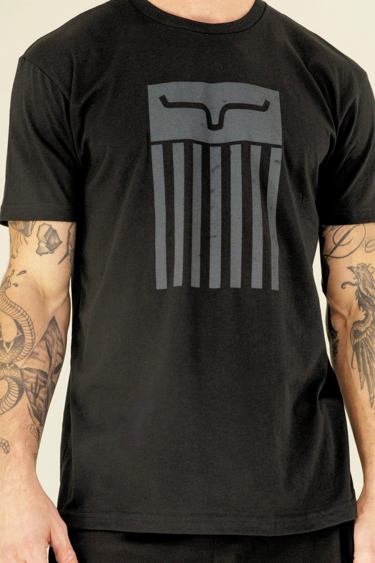 Kimes Ranch Cody Tee Shirt in Black with a large graphic featuring a stylized Kimes Ranch logo and vertical stripes