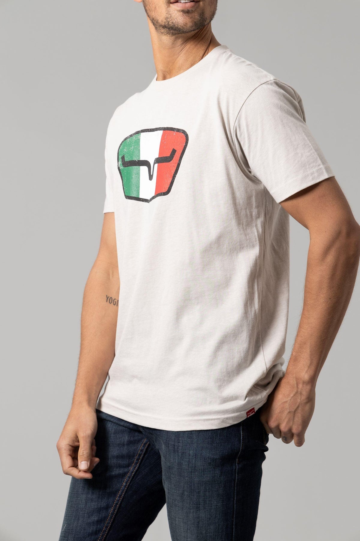 Kimes Ranch Tri-Color Tee in Sand, side view, with a graphic of a the Kimes Ranch logo in green, white, and red