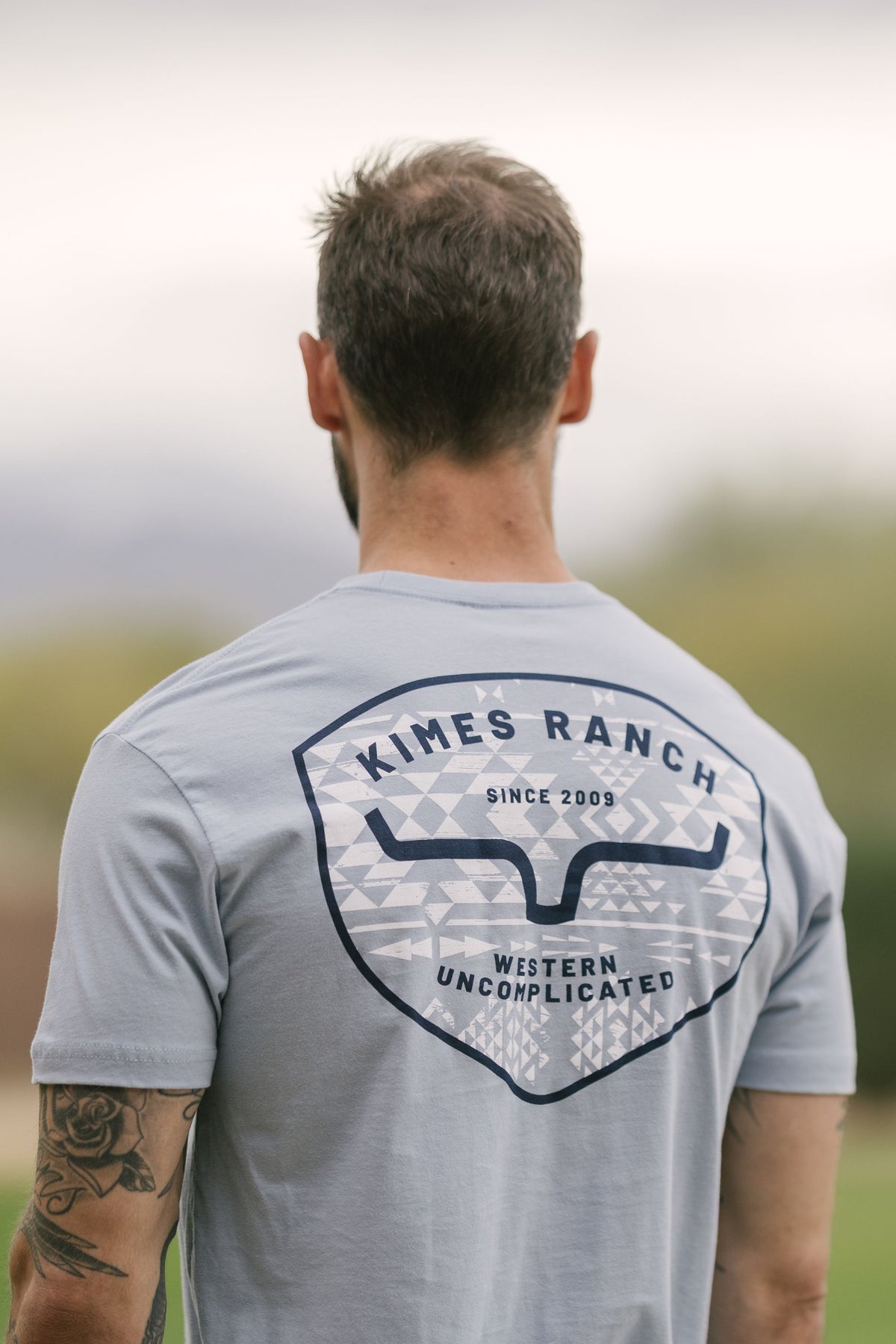 Kimes Ranch Honor, back view, shirt in Stonewash with a back graphic featuring the Kimes Ranch logo