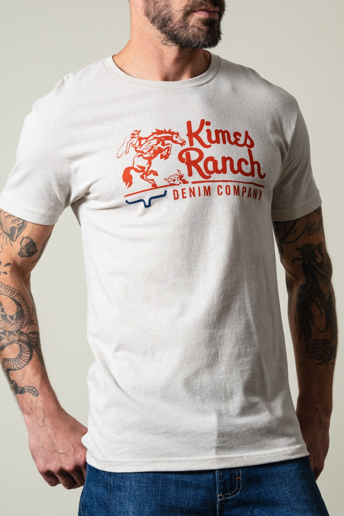 Kimes Ranch Davona Dale short sleeve sand t-shirt with red Kimes Ranch logo and blue longhorn graphic on chest